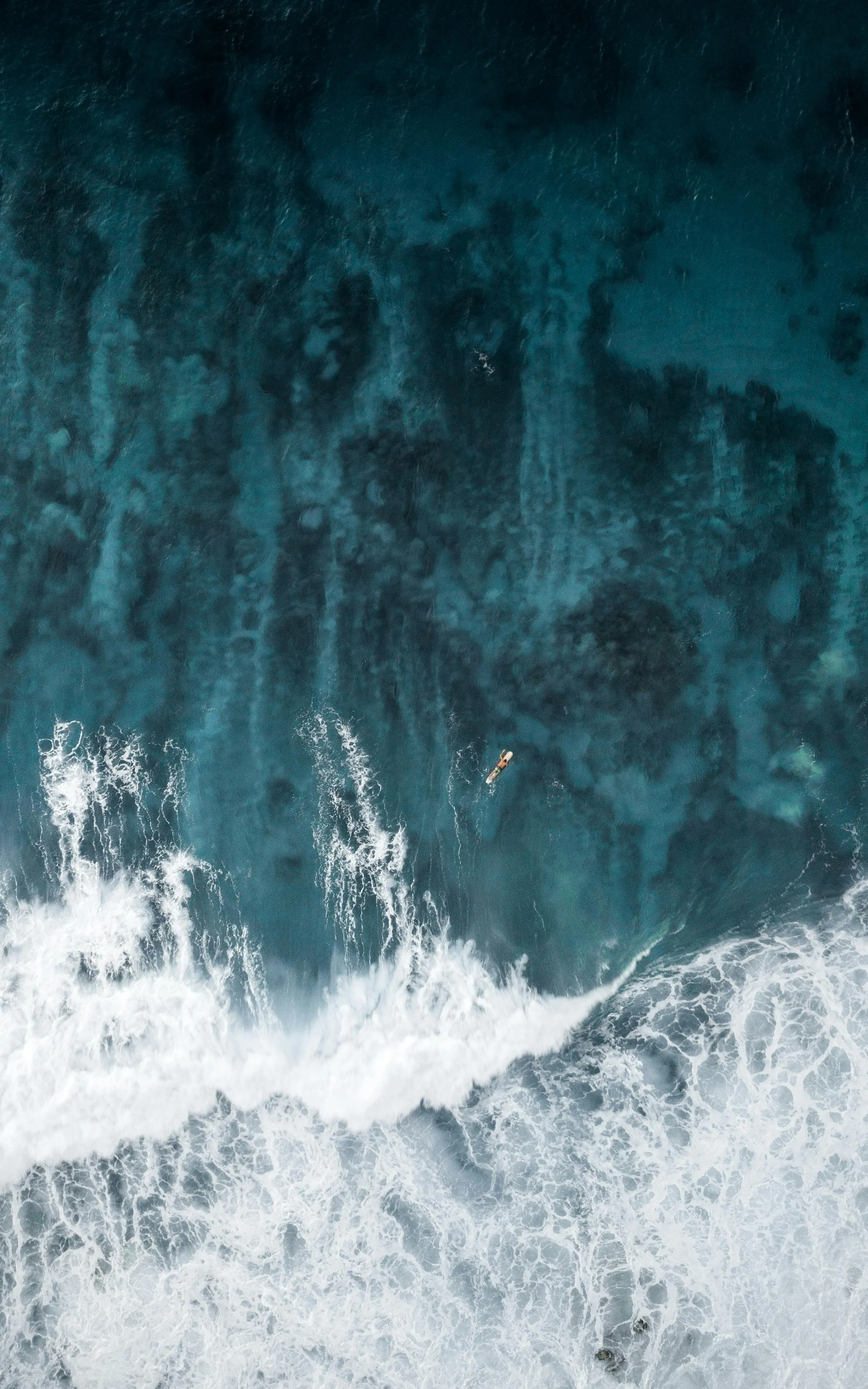 Aerial view of ocean waves crashing on the rocky shore below