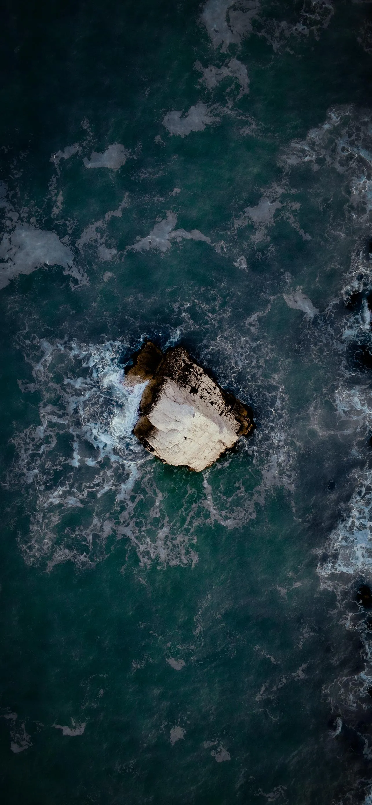 Aerial view of ocean with small boat floating alone