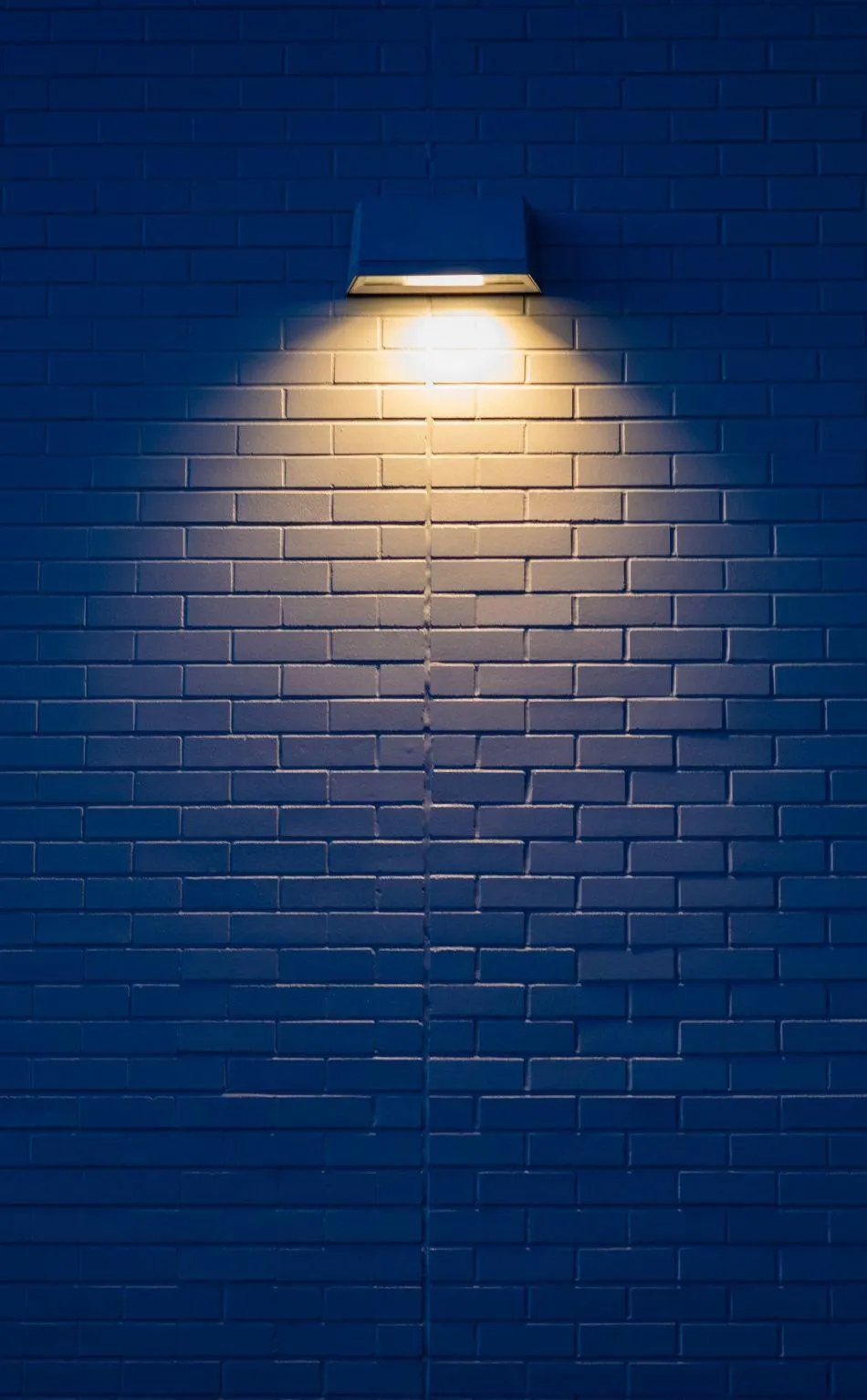Blue brick wall illuminated by warm light from above 4K