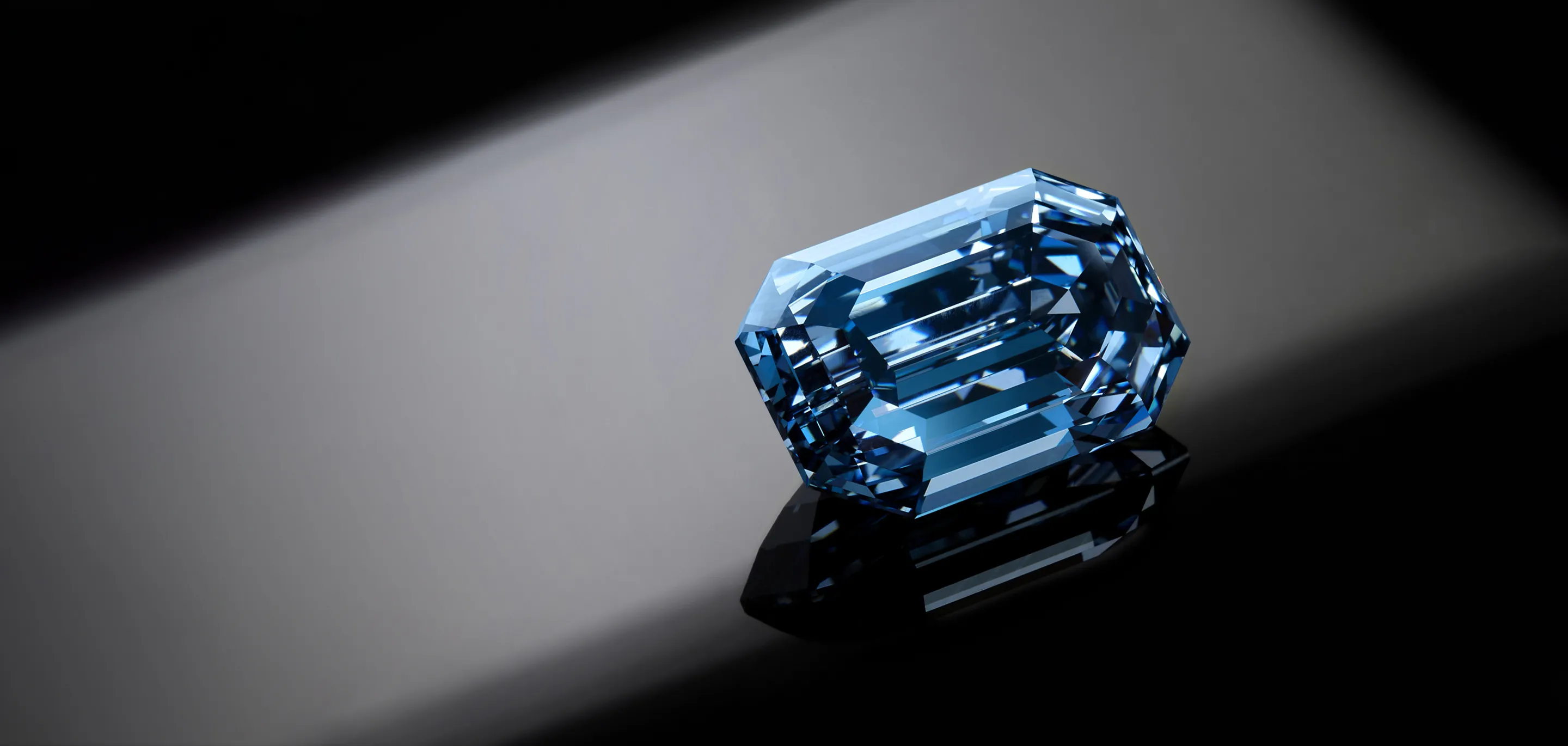Blue gemstone on a black surface with detailed crystal cuts