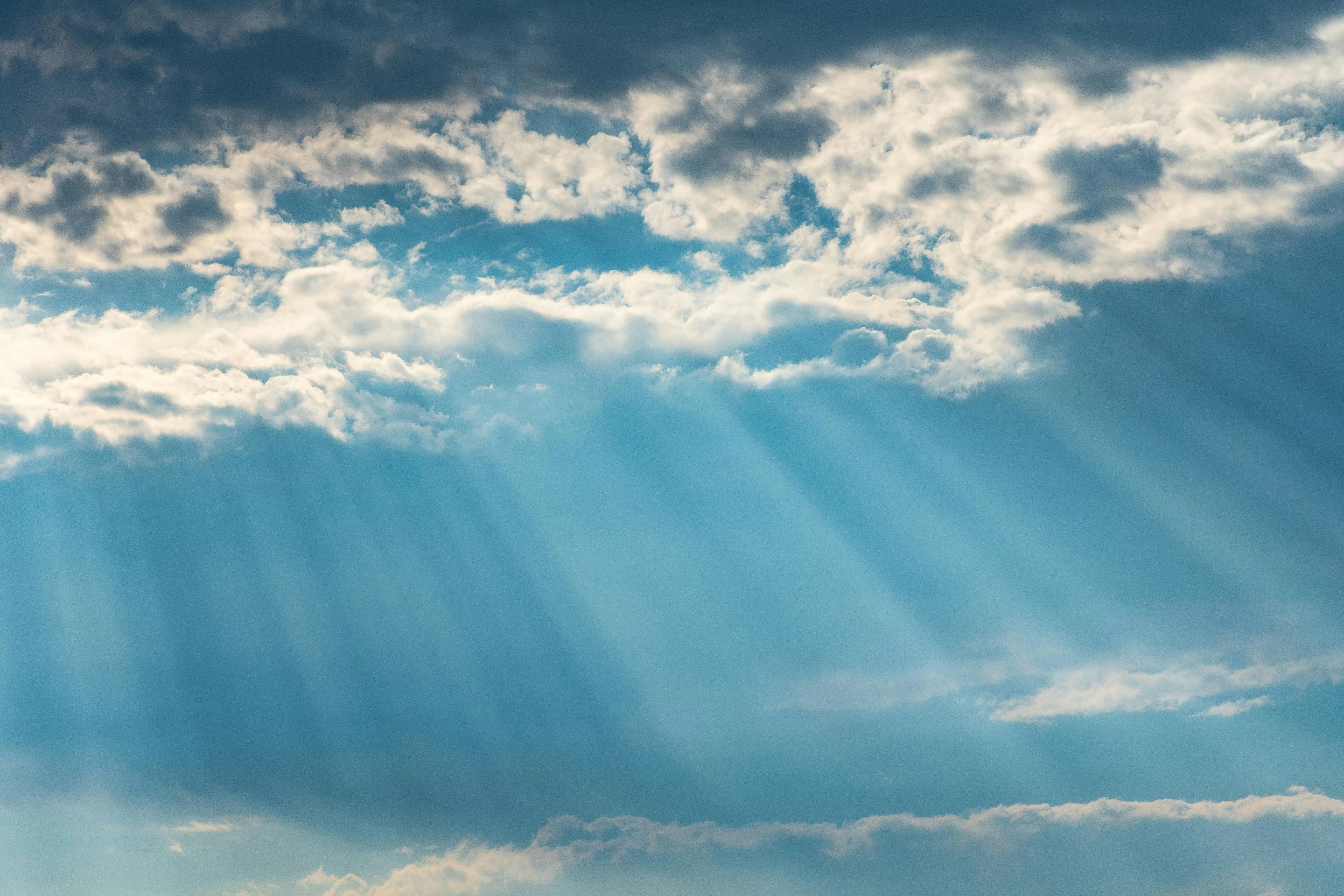Blue sky with clouds and sun rays streaming down Wallpaper