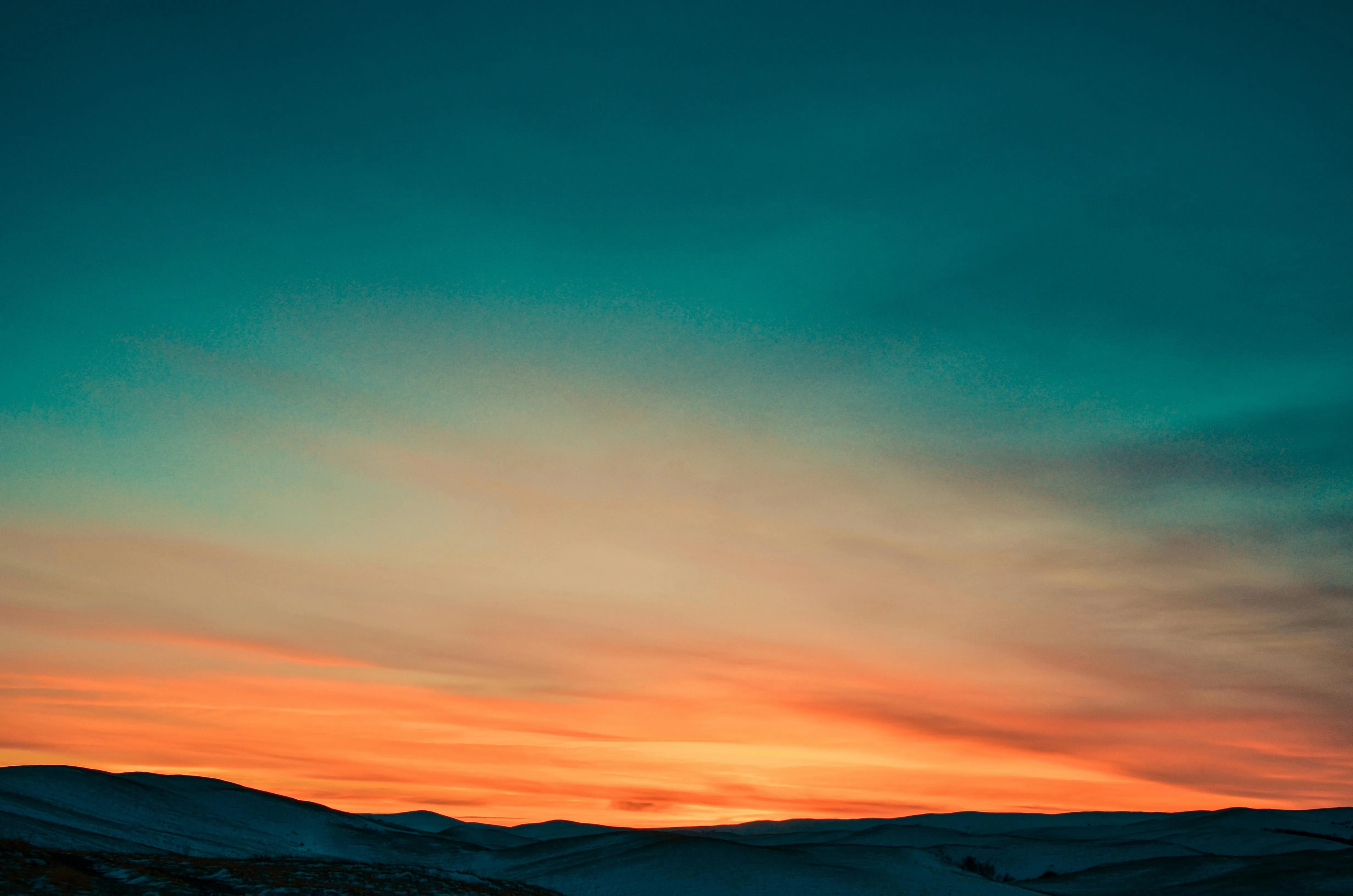 Calm sunset over the hills with a deep orange sky Wallpaper