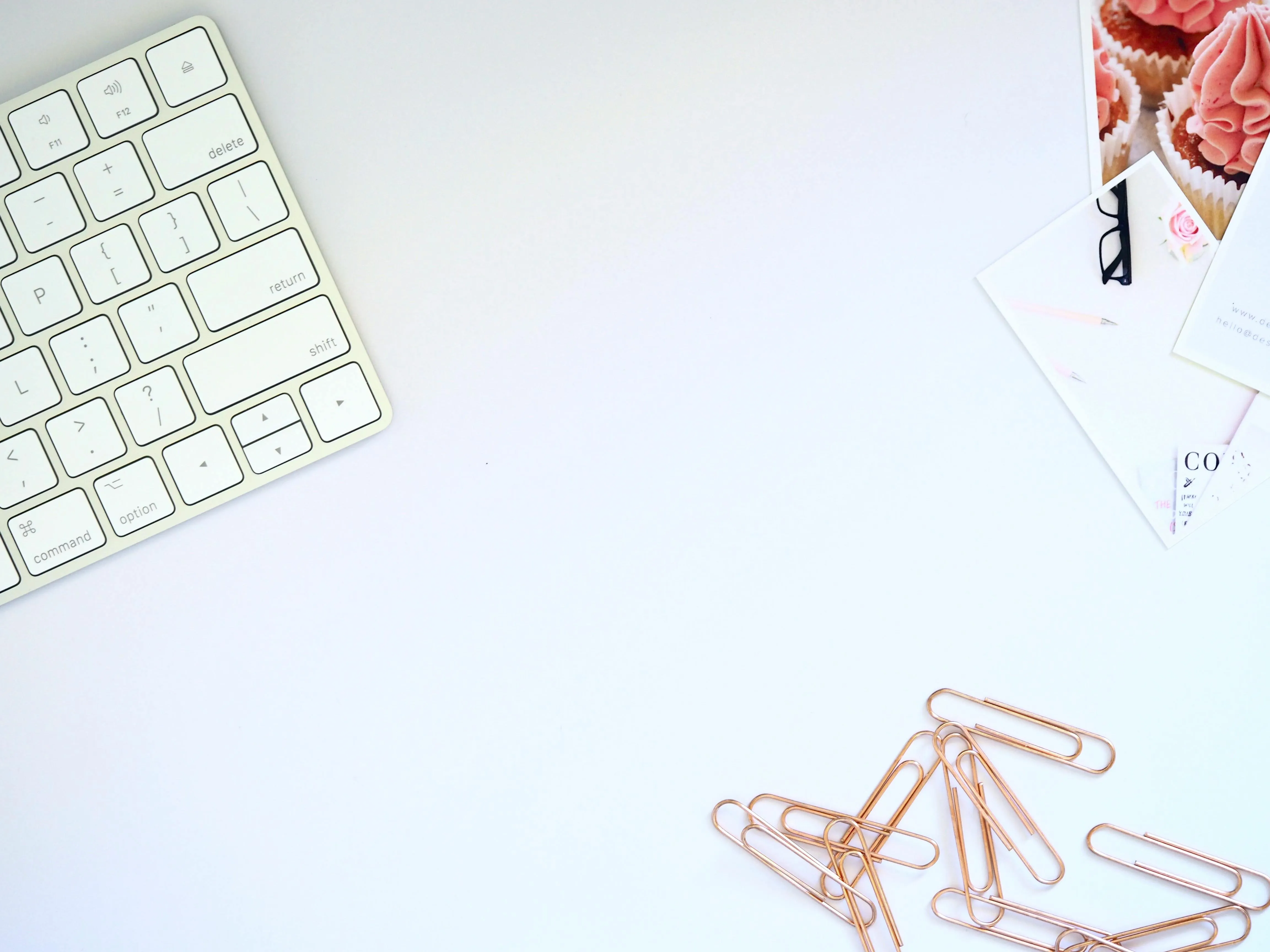 Clean white workspace with keyboard and paperclips Wallpaper