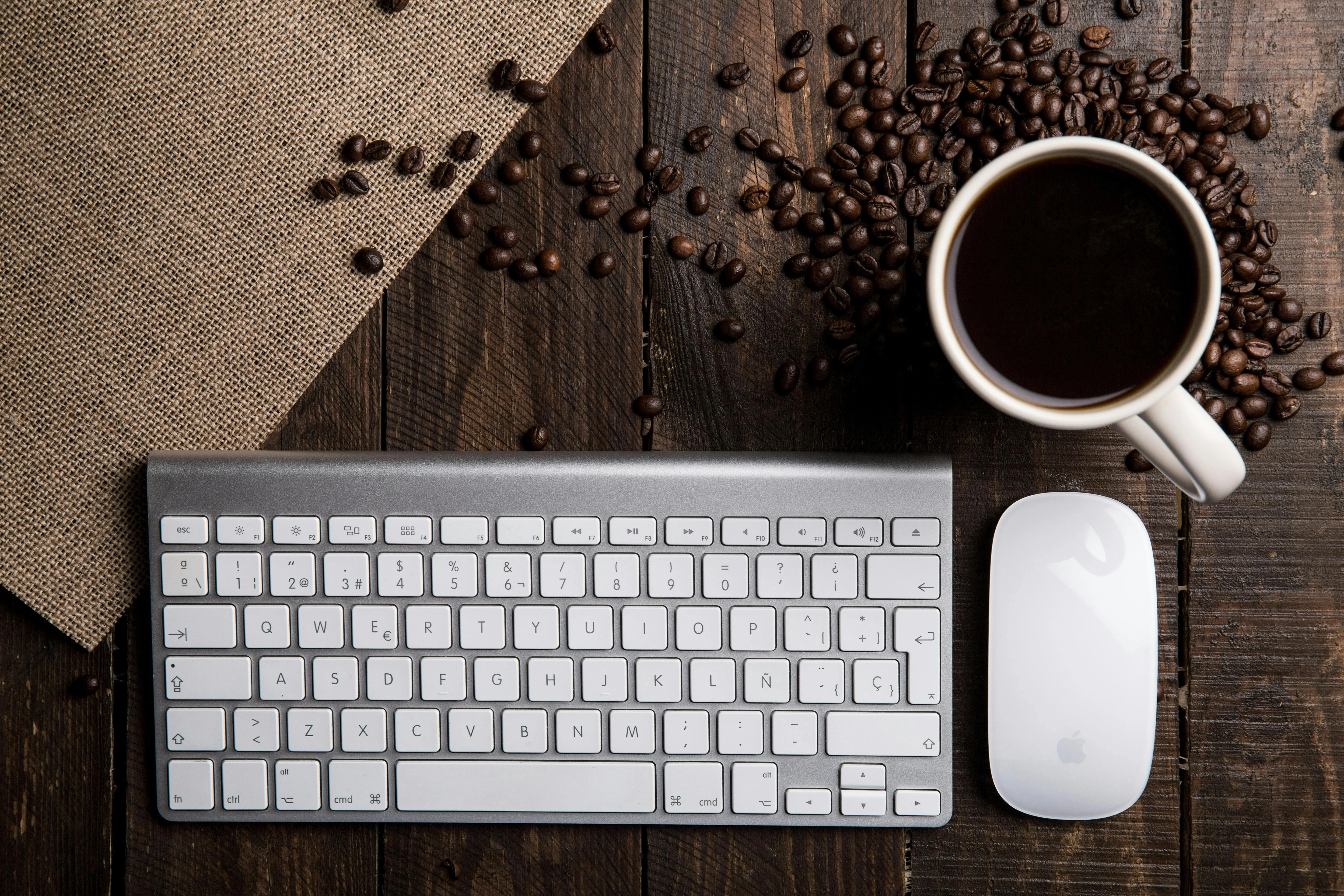 Coffee cup with beans keyboard and mouse on wooden table