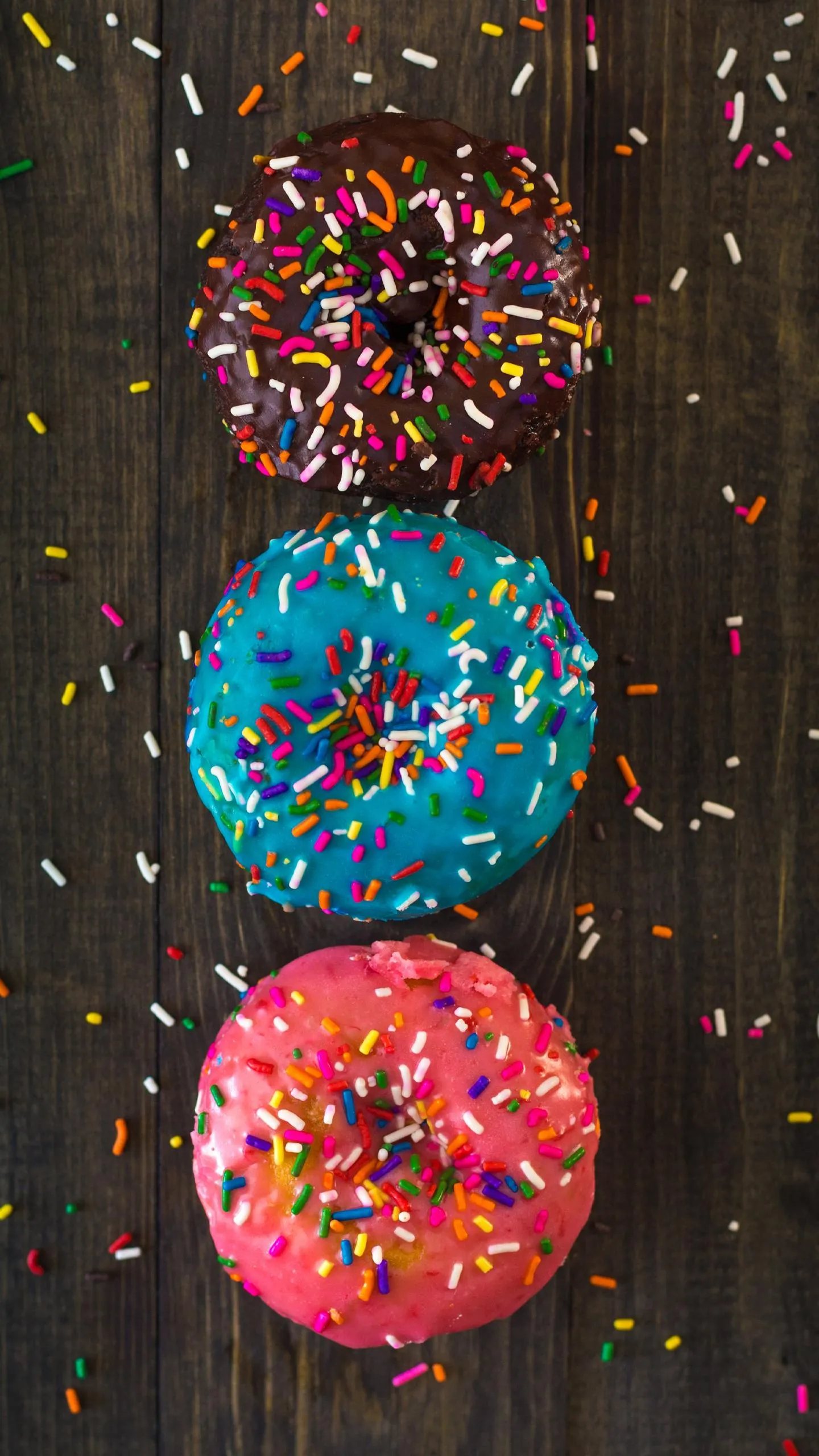 Colorful Frosted Donuts with Rainbow Sprinkles on Wood