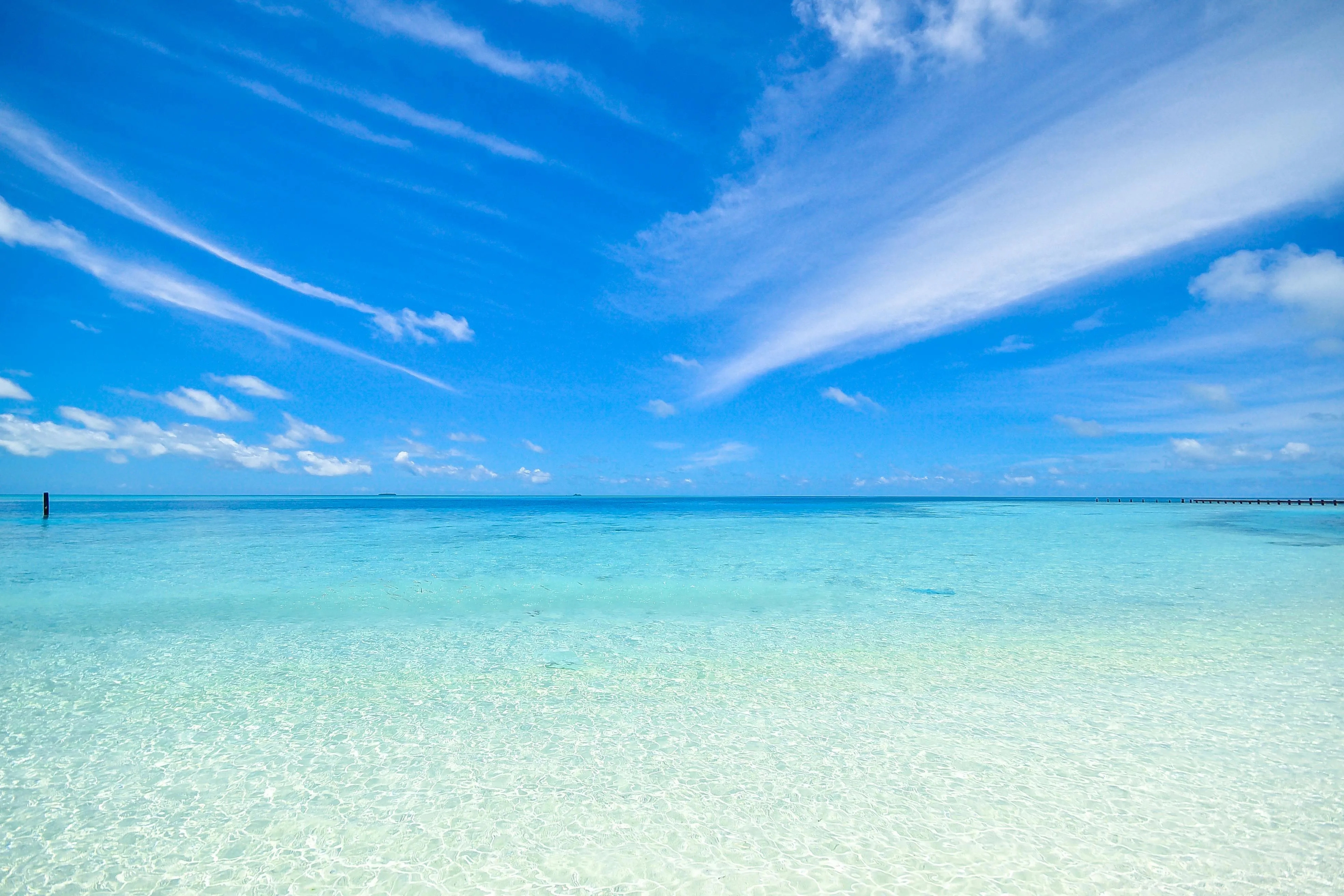 Crystal clear ocean water under a bright blue sky Wallpaper