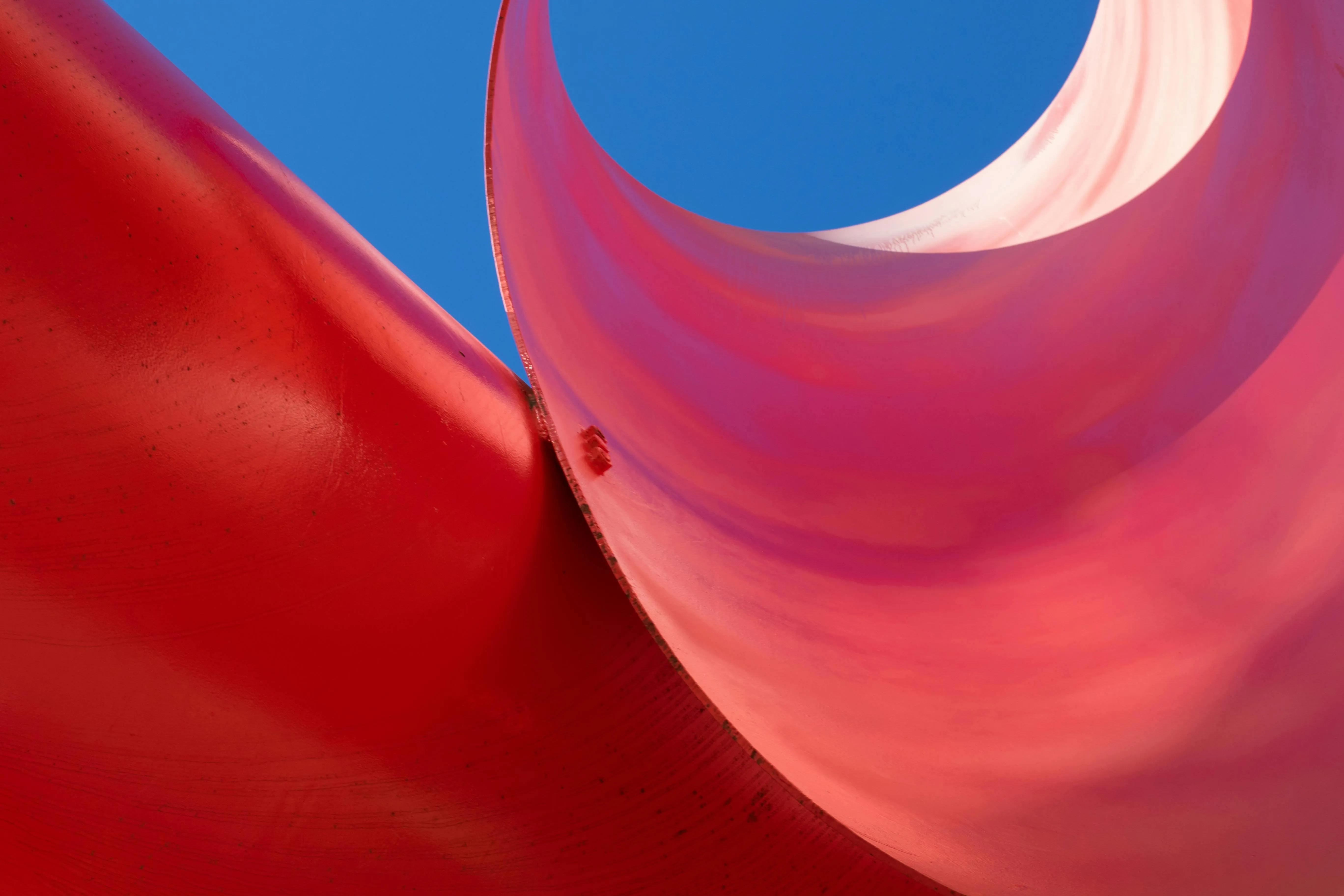 Curved red abstract shape with clear blue sky background