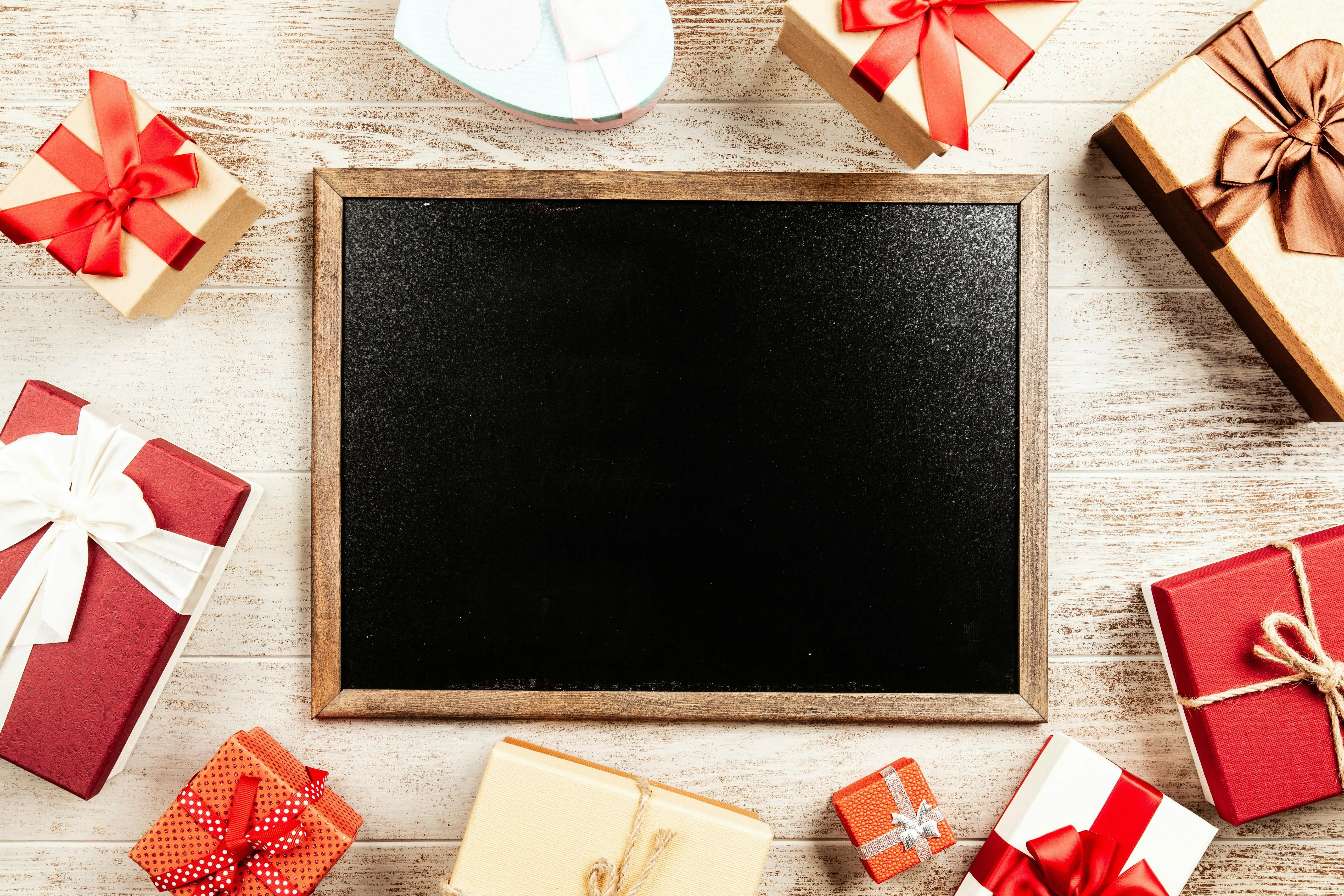 Festive gift boxes surrounding a blank blackboard on table