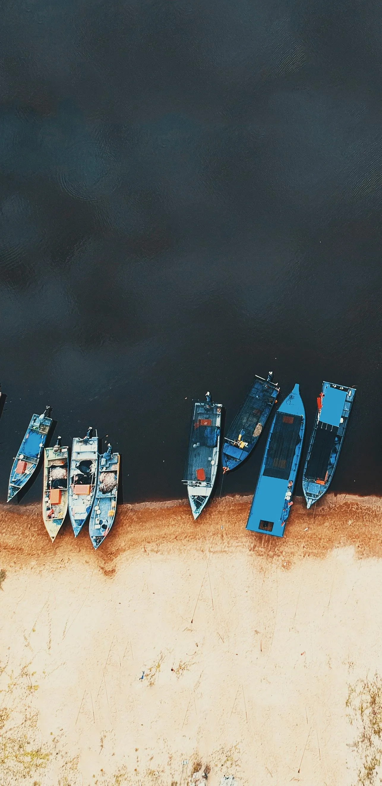 Fishing Boats Rest on Riverbank During Calm Afternoon