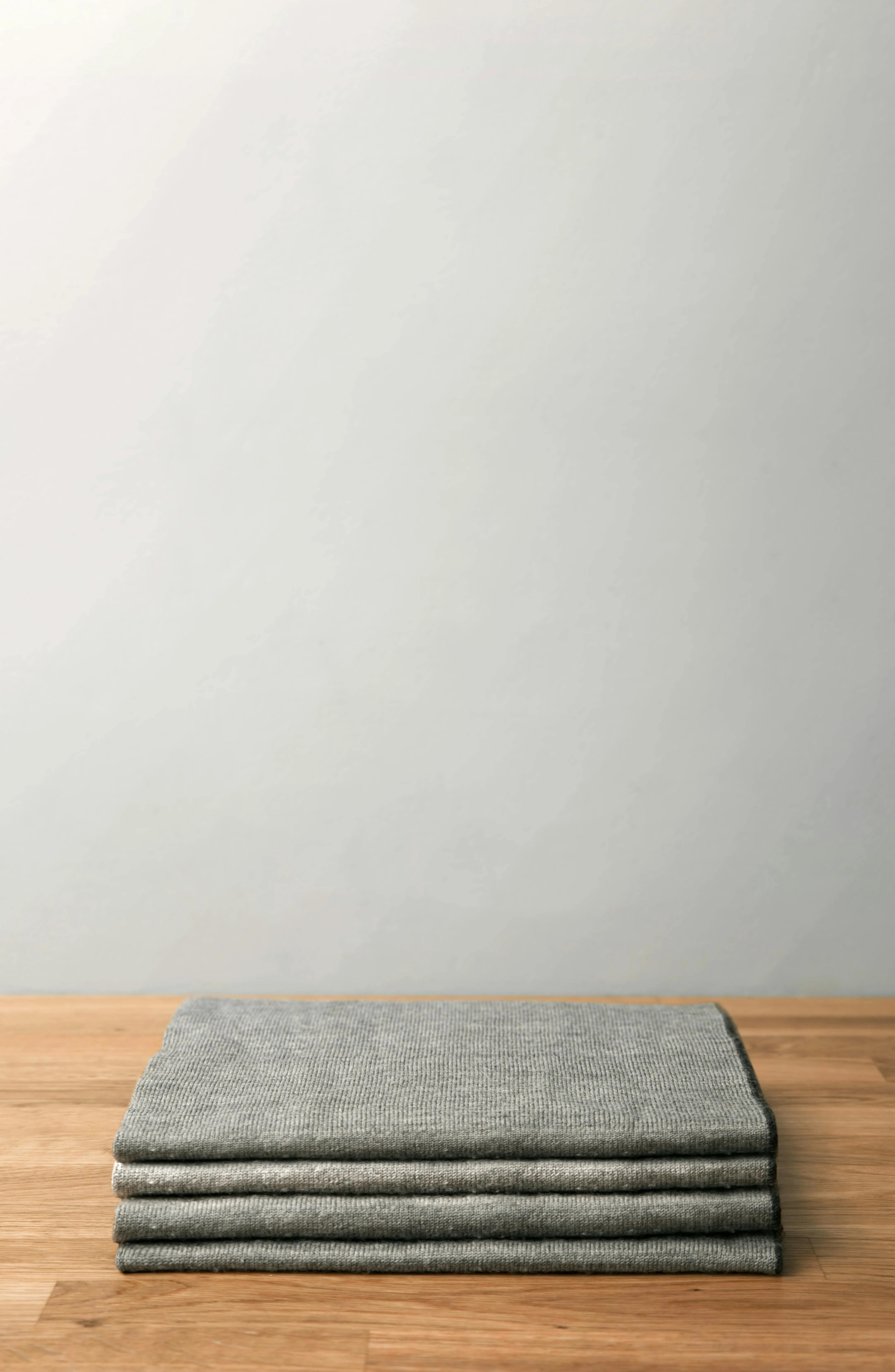 Folded gray fabric on a wooden table with a light wall image
