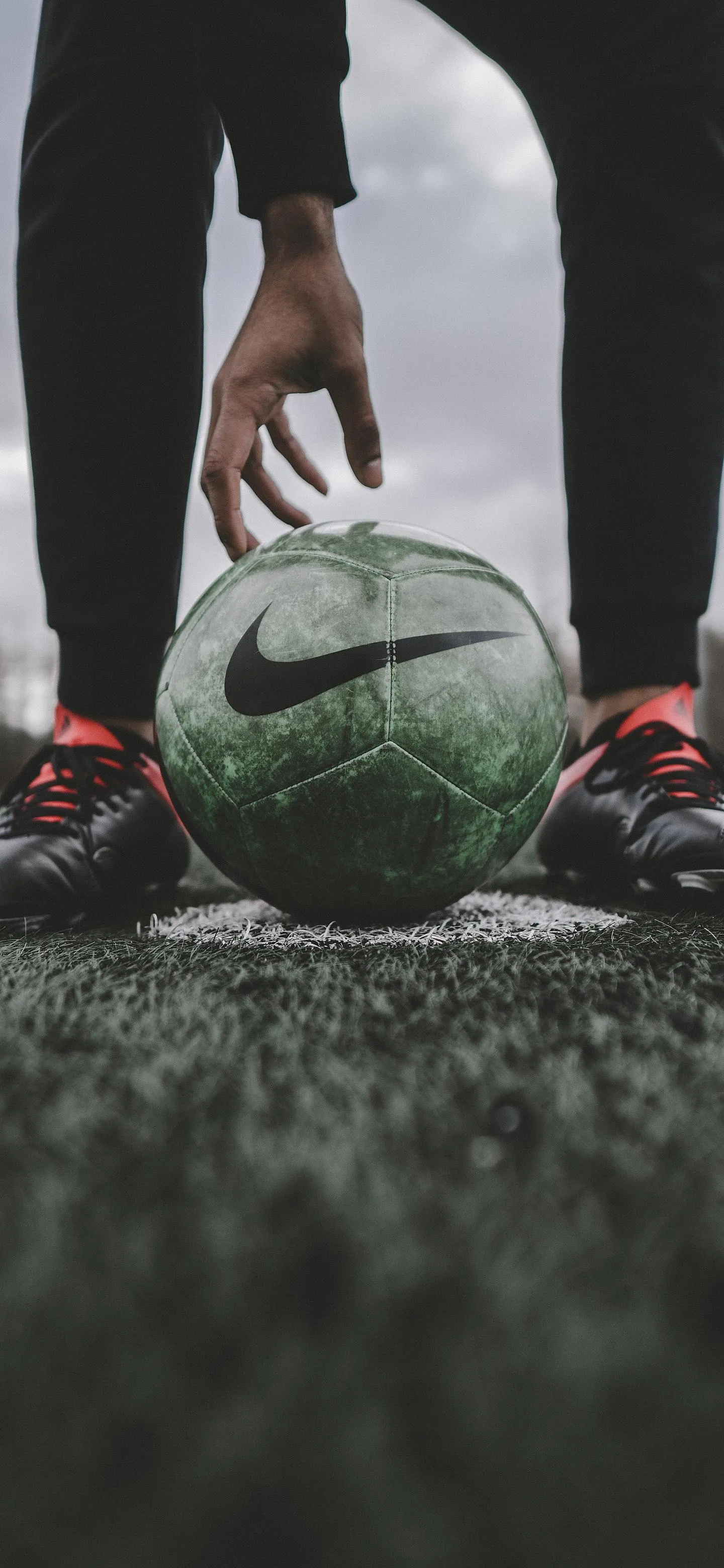 Football Player Kicking Ball on Muddy Rainy Field Wallpaper
