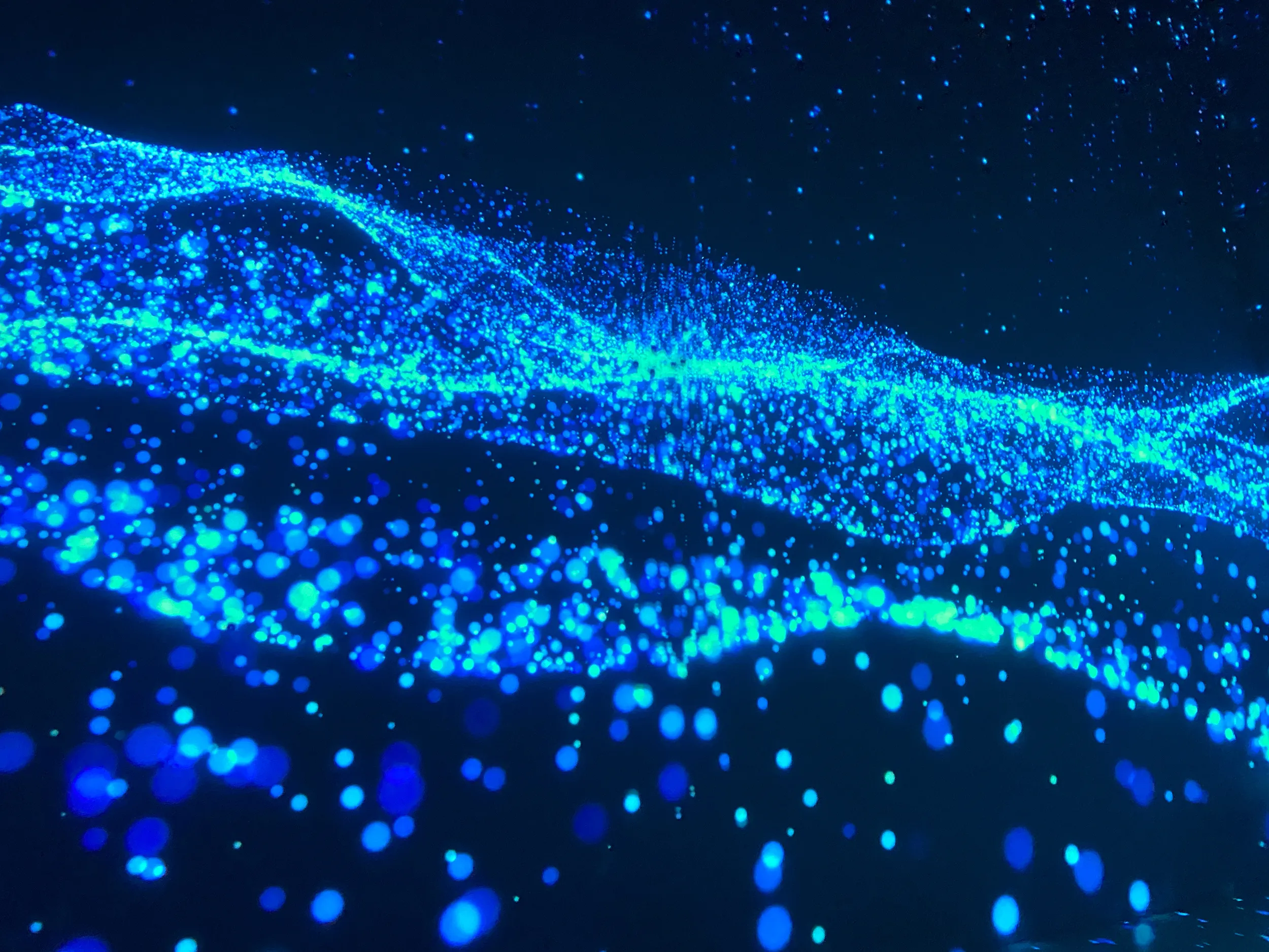 Glowing blue particles forming waves on a dark backdrop