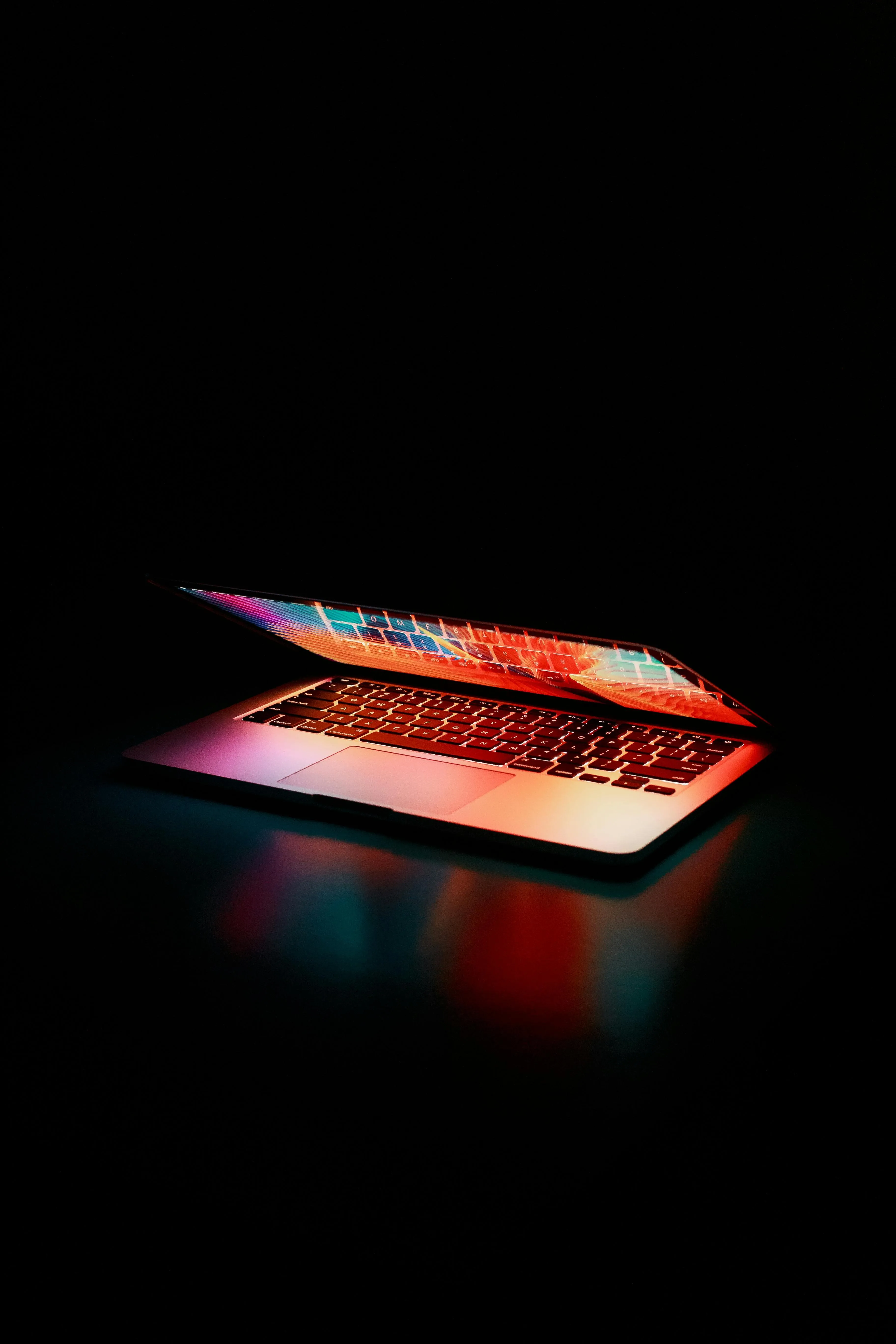 Glowing laptop in dark room with colourful neon lighting