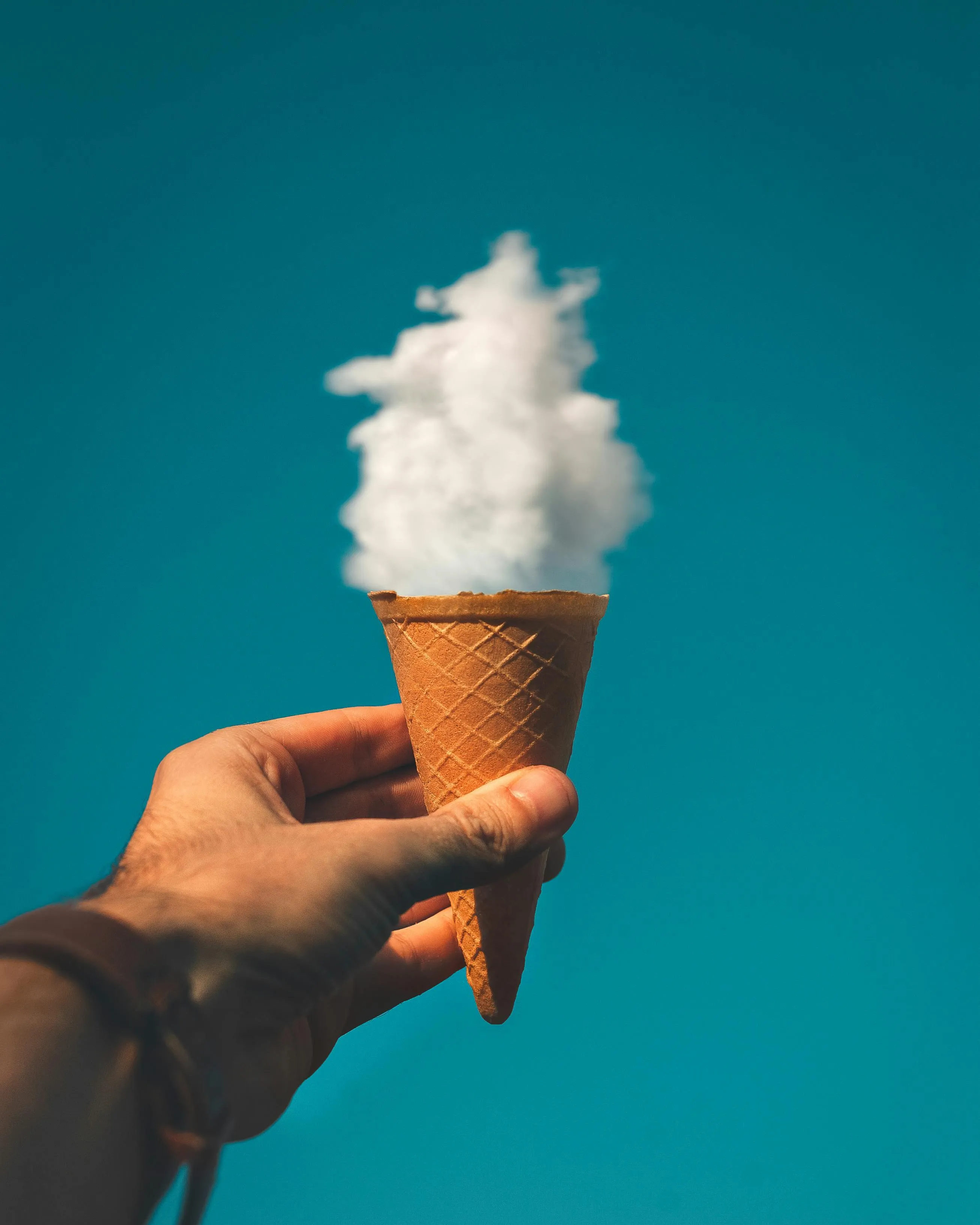 Hand holding an ice cream cone with cloud as a scoop image