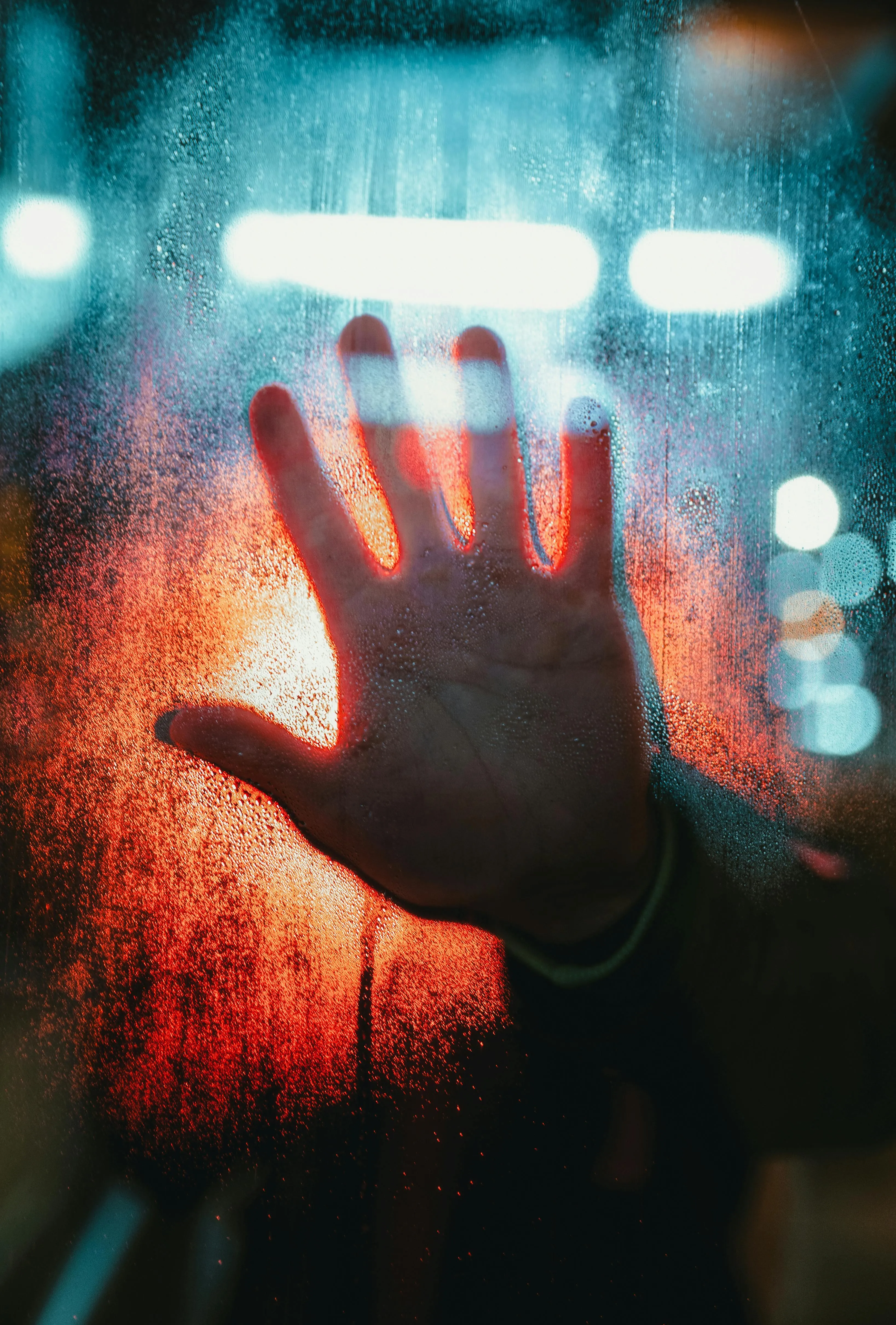 Hand pressed on foggy glass with colourful lights behind 4K
