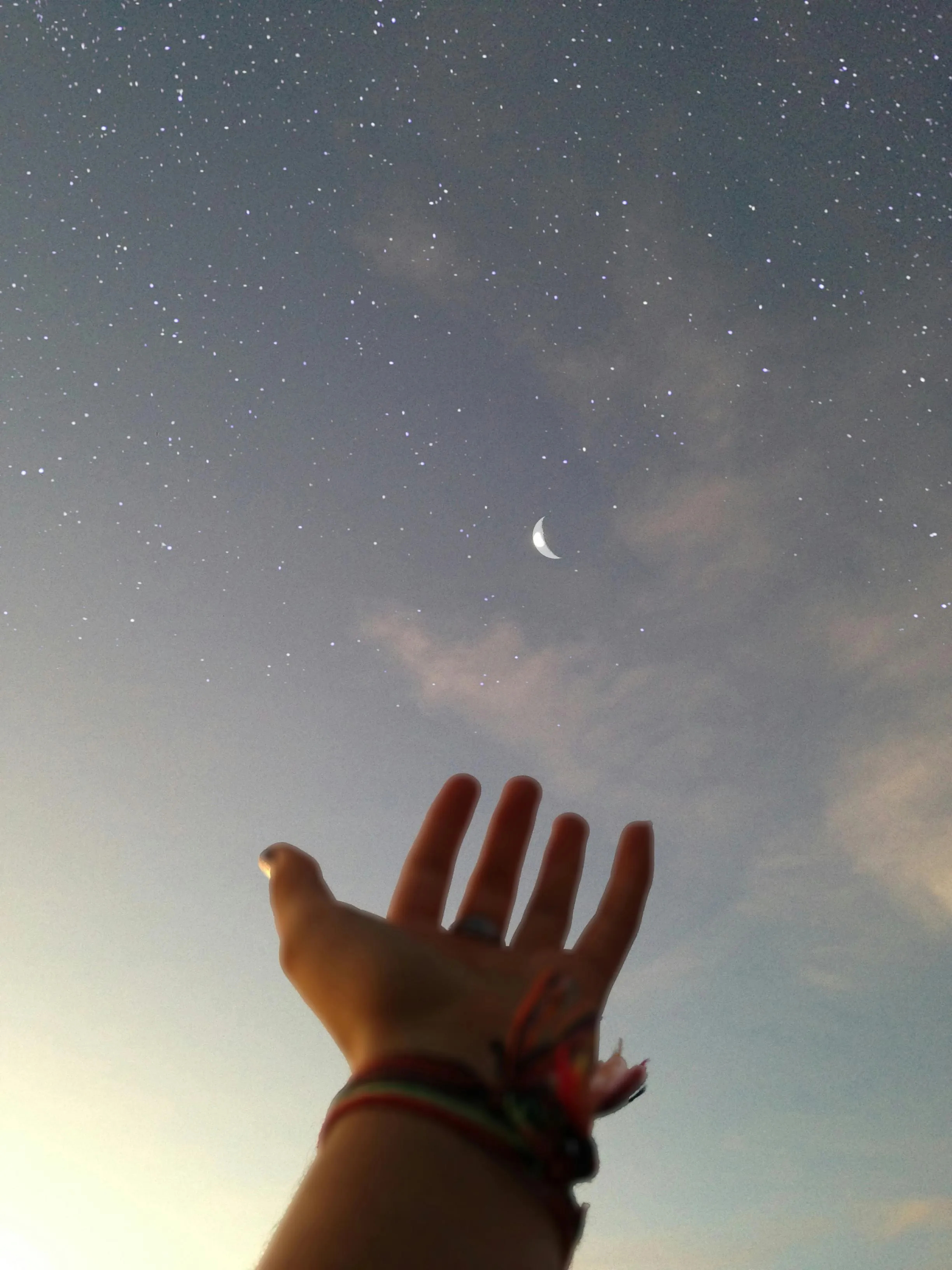 Hand reaching up to the sky with stars and a crescent moon