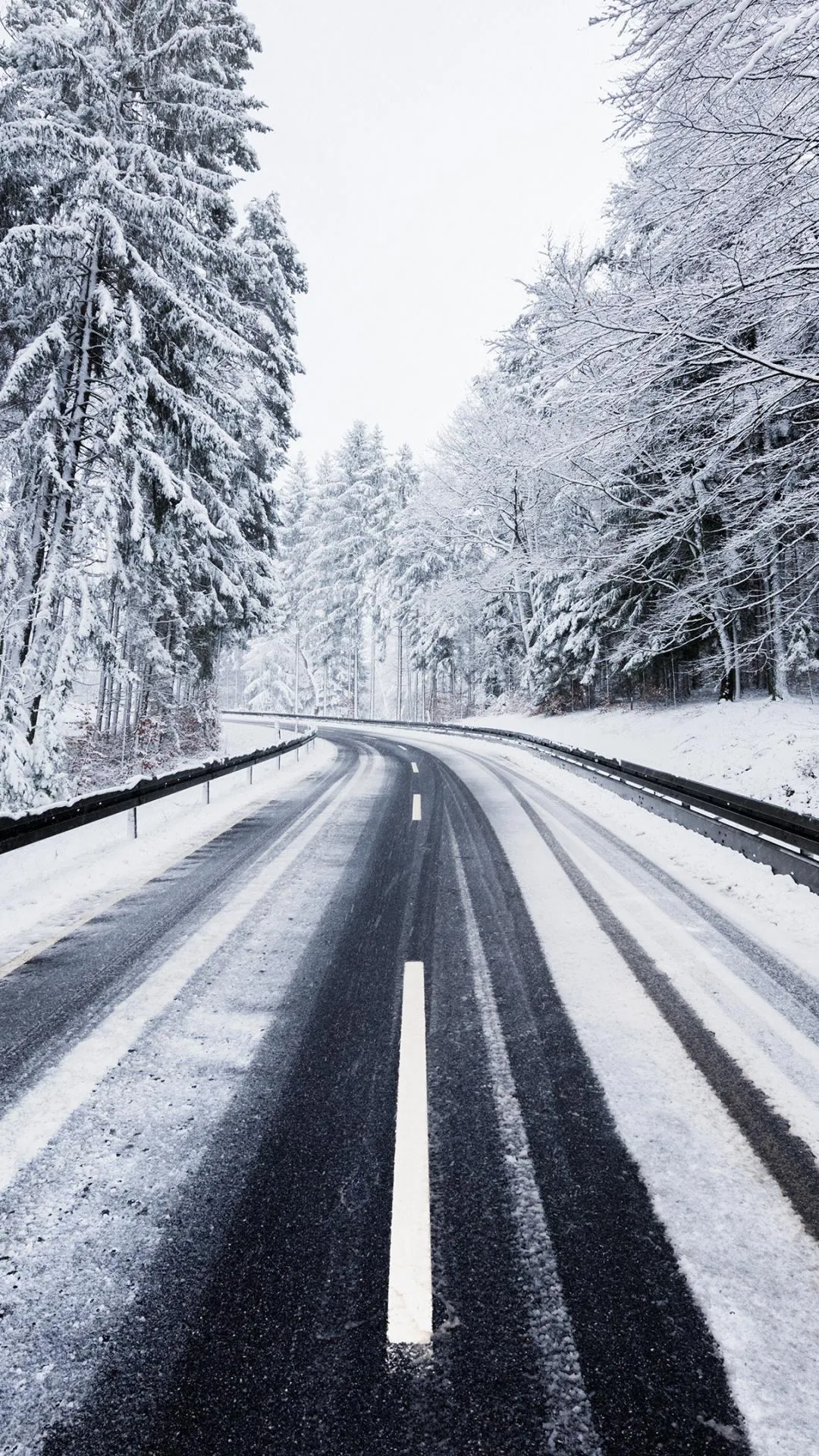 Icy Winter Road Through Forest Covered in Heavy Snow