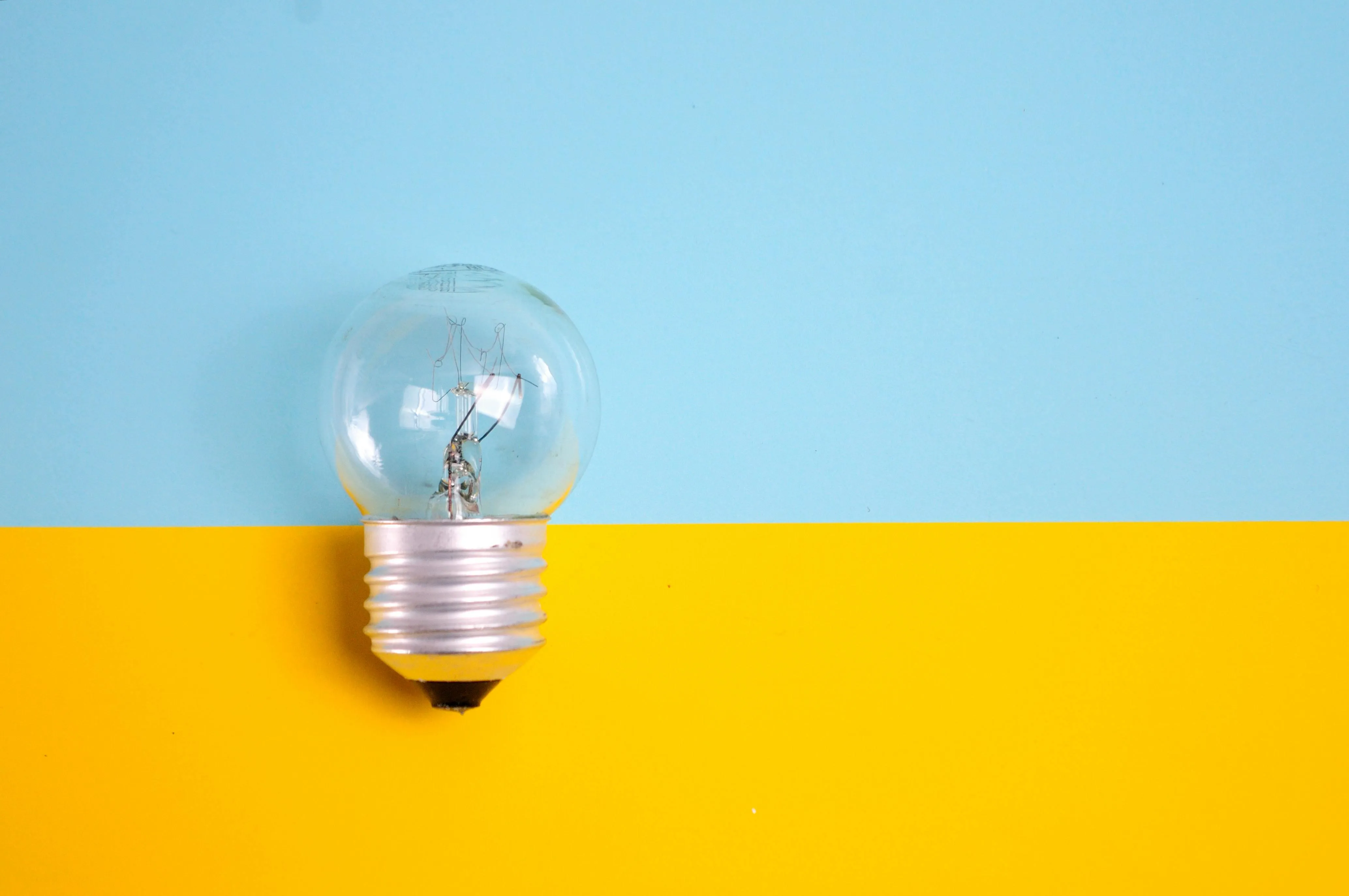 Light bulb against a blue and yellow split colour background