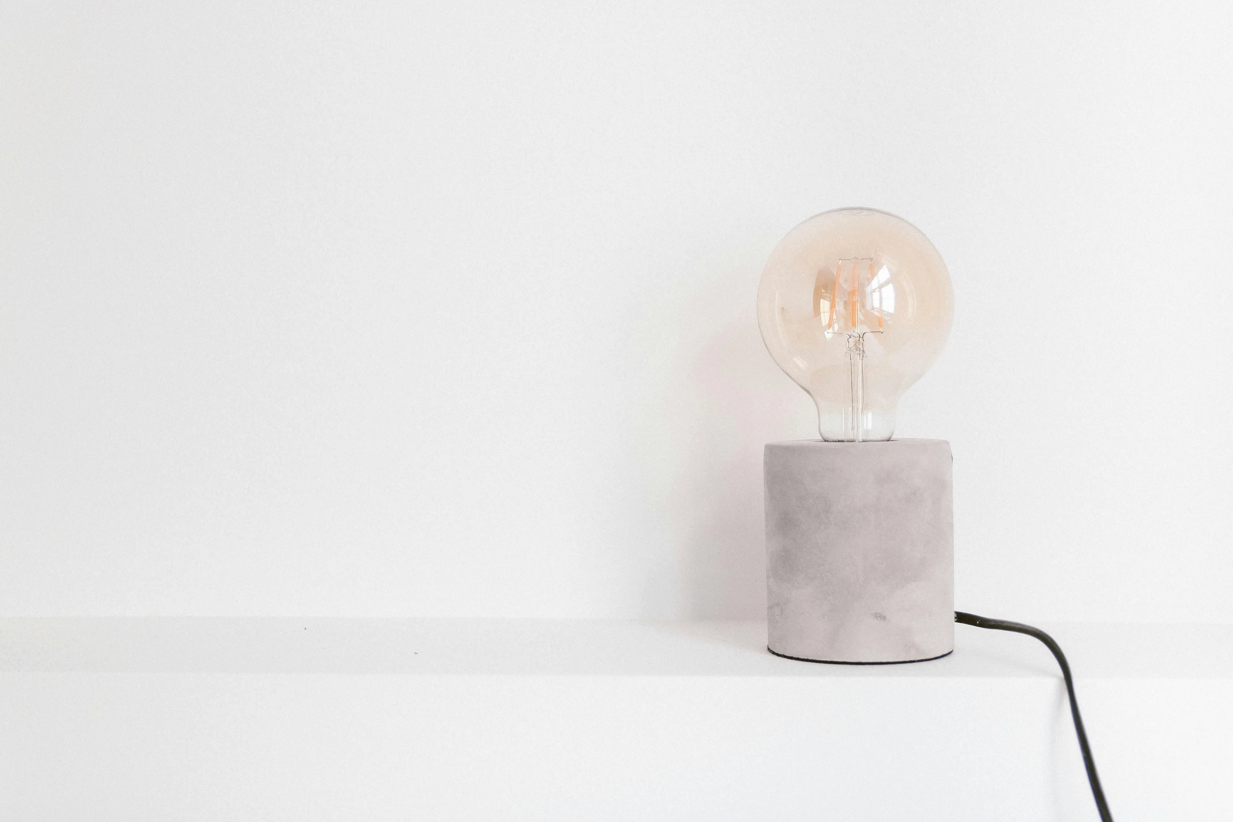 Light bulb on a small concrete base against a white wall