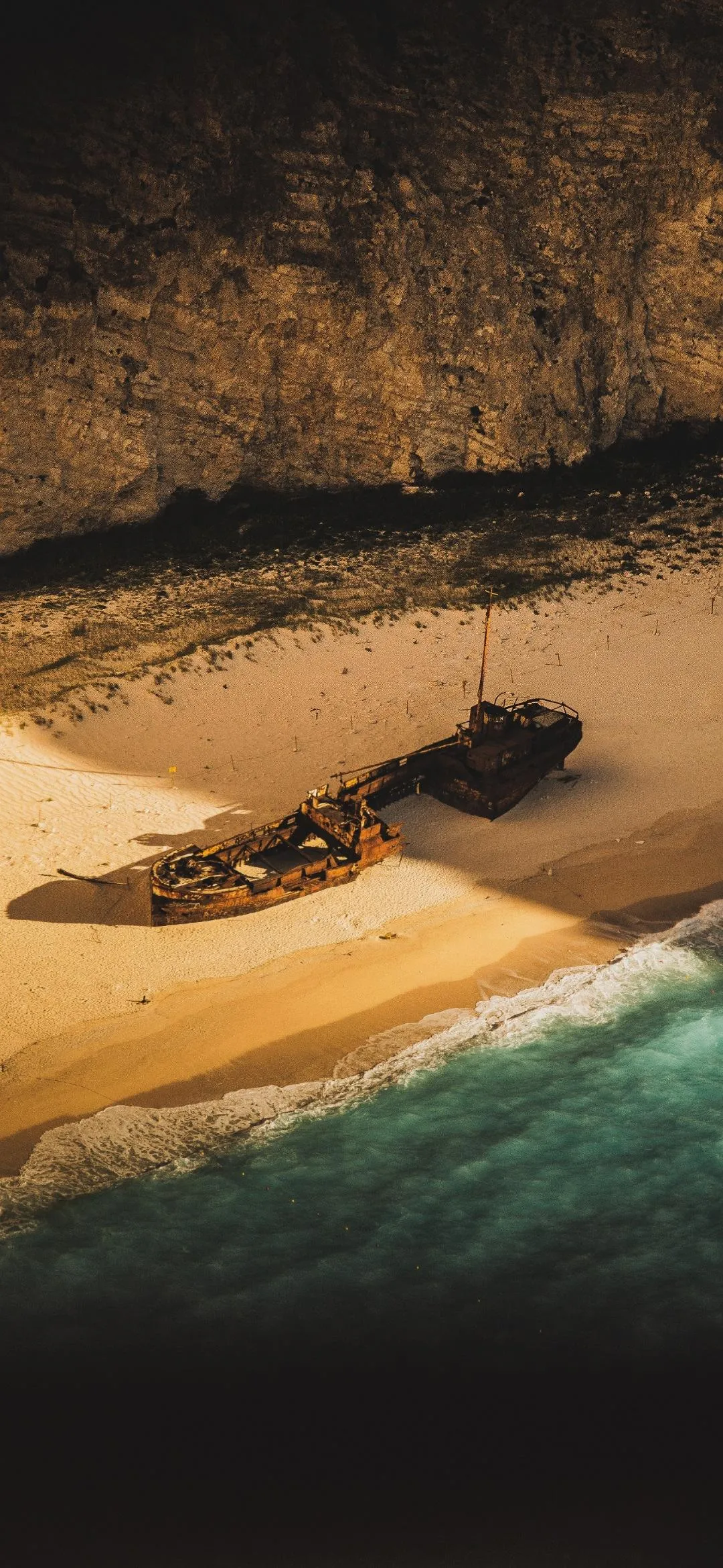Lone Boat on Sandy Beach with Ocean Waves and Sunset