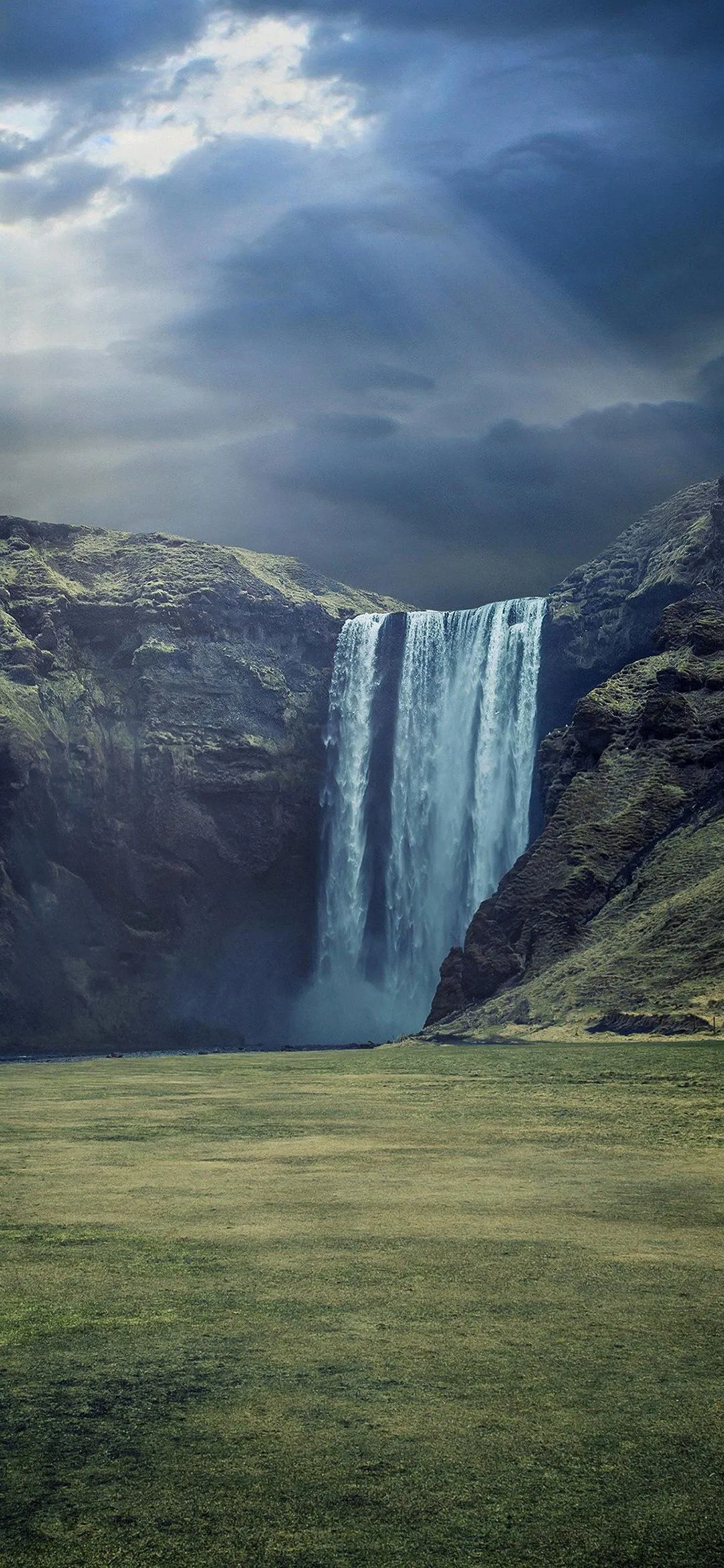 Majestic waterfall under cloudy dramatic sky Wallpaper