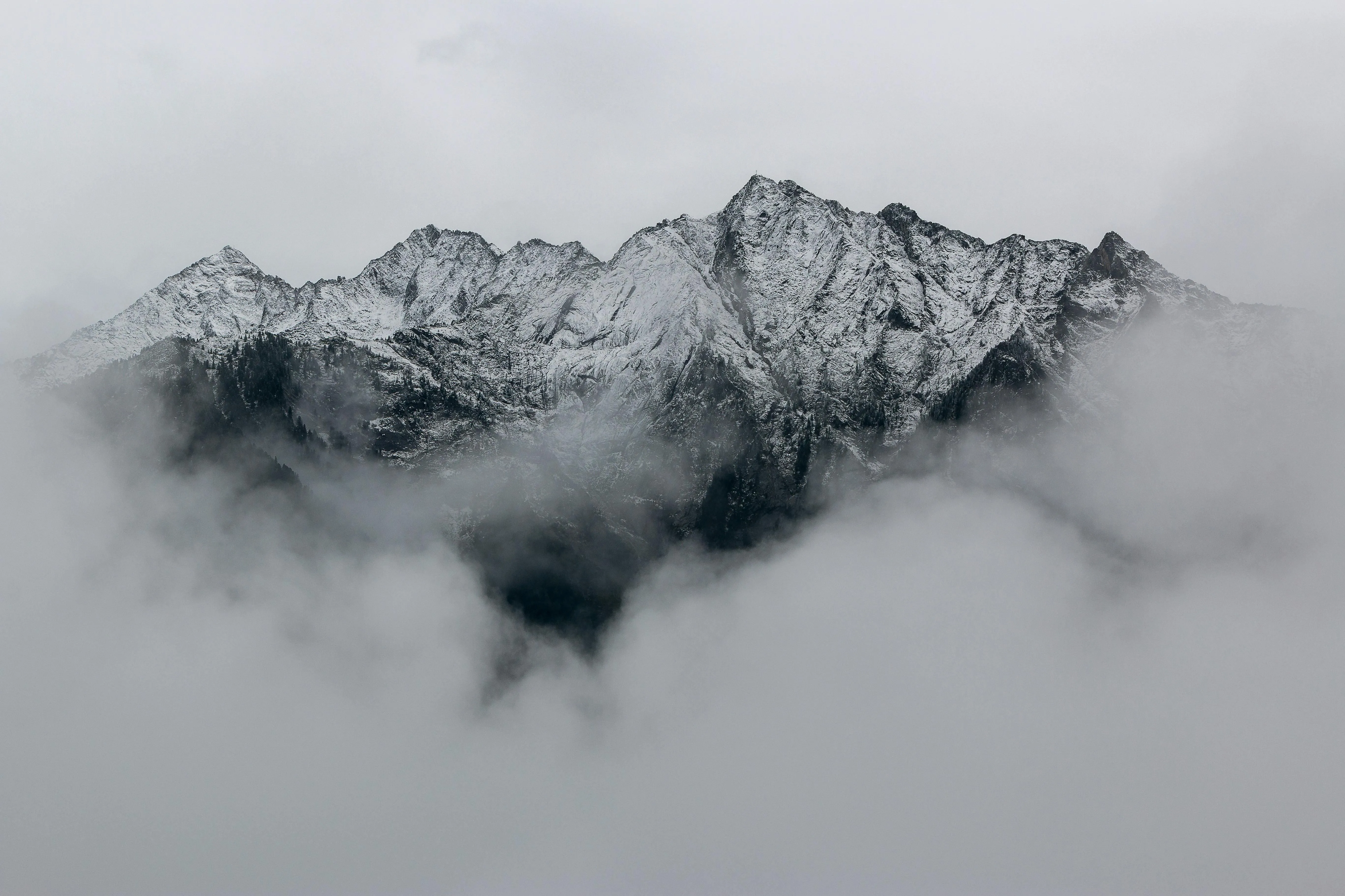 Misty mountain peaks rising above with thick fog and clouds