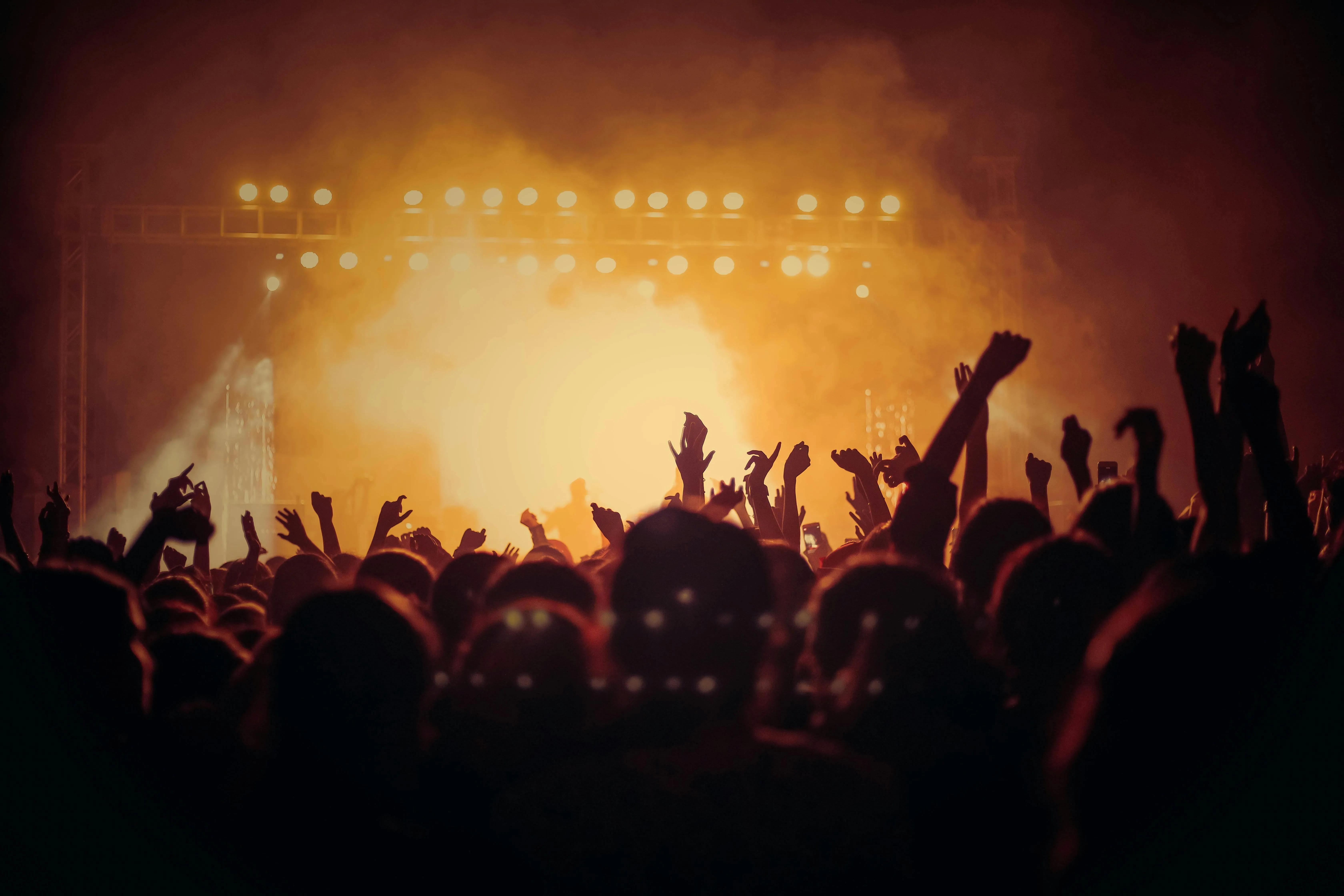 Music concert crowd cheering under a warm bright lighting