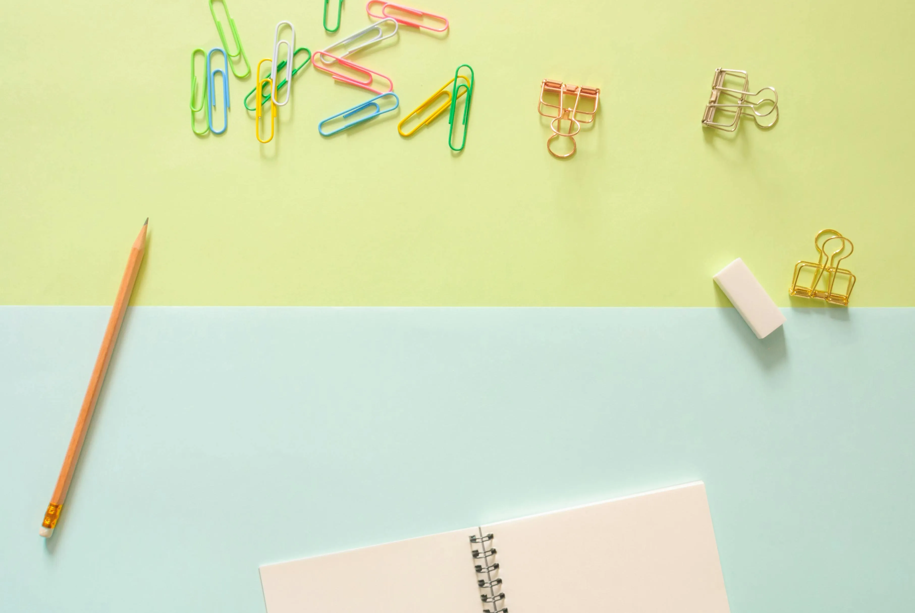 Neatly arranged office supplies on a pastel coloured desk