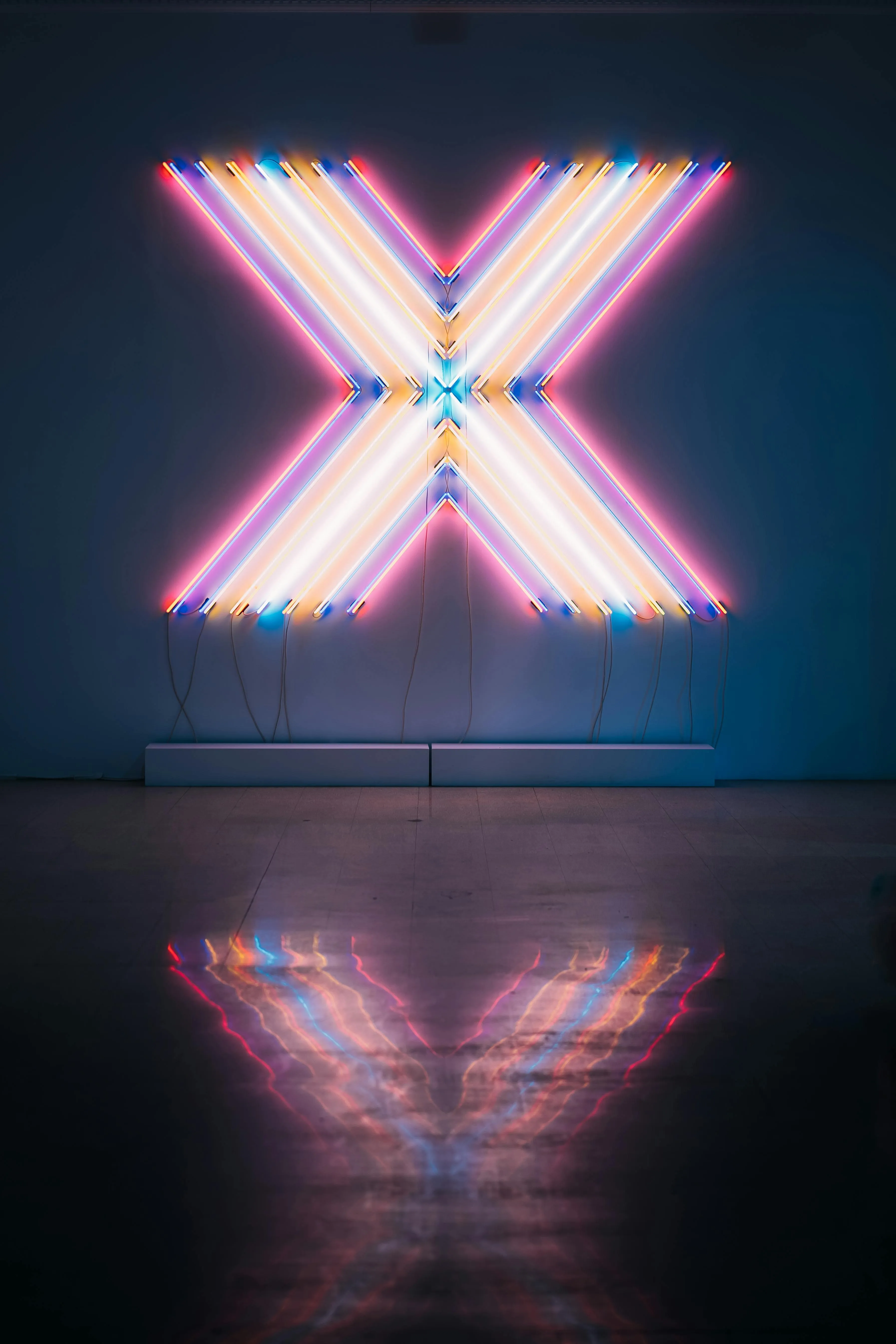Neon light shaped as the letter X with reflection below 4K