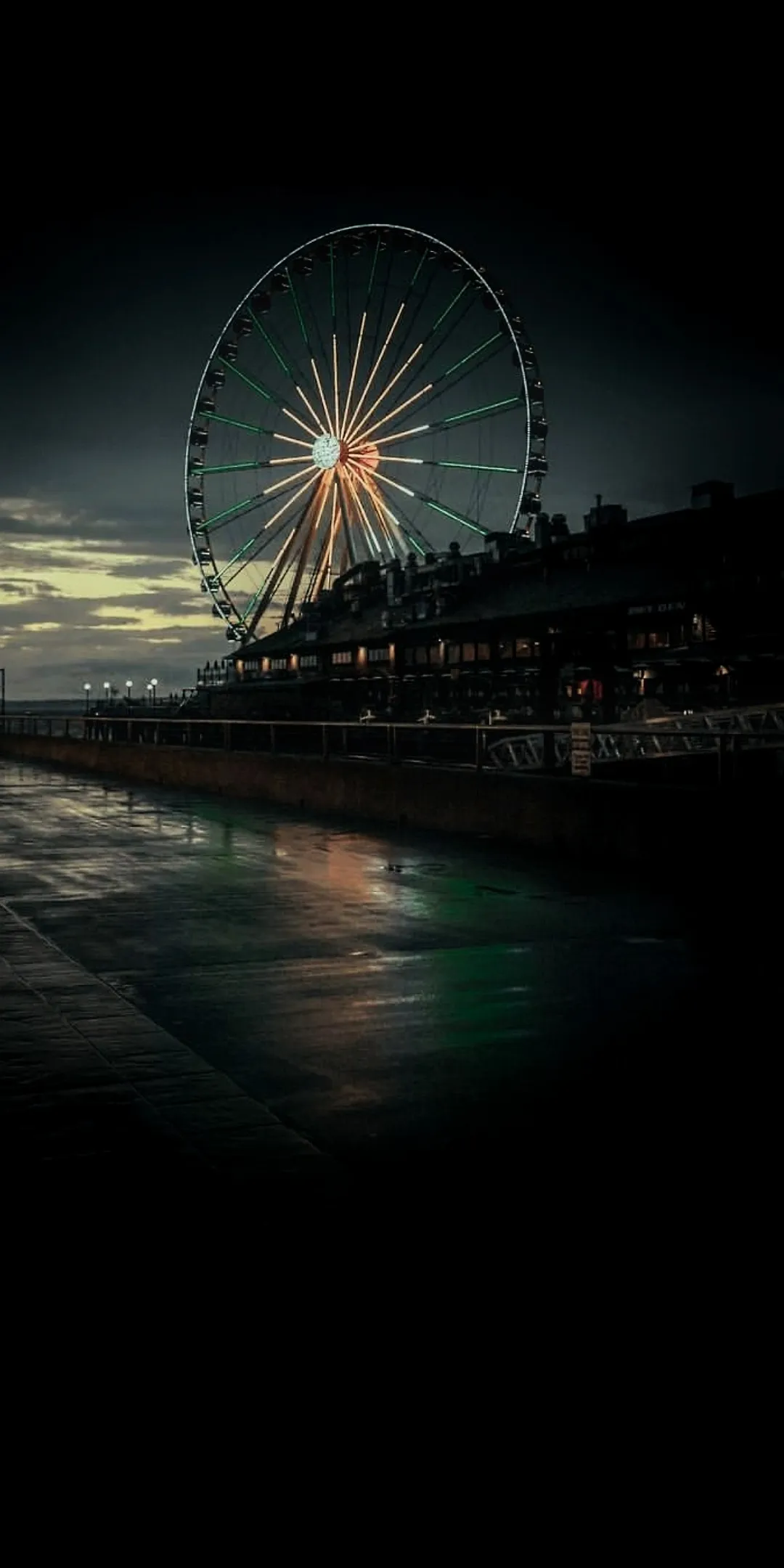 Night scene of ferris wheel beside a glowing city bay