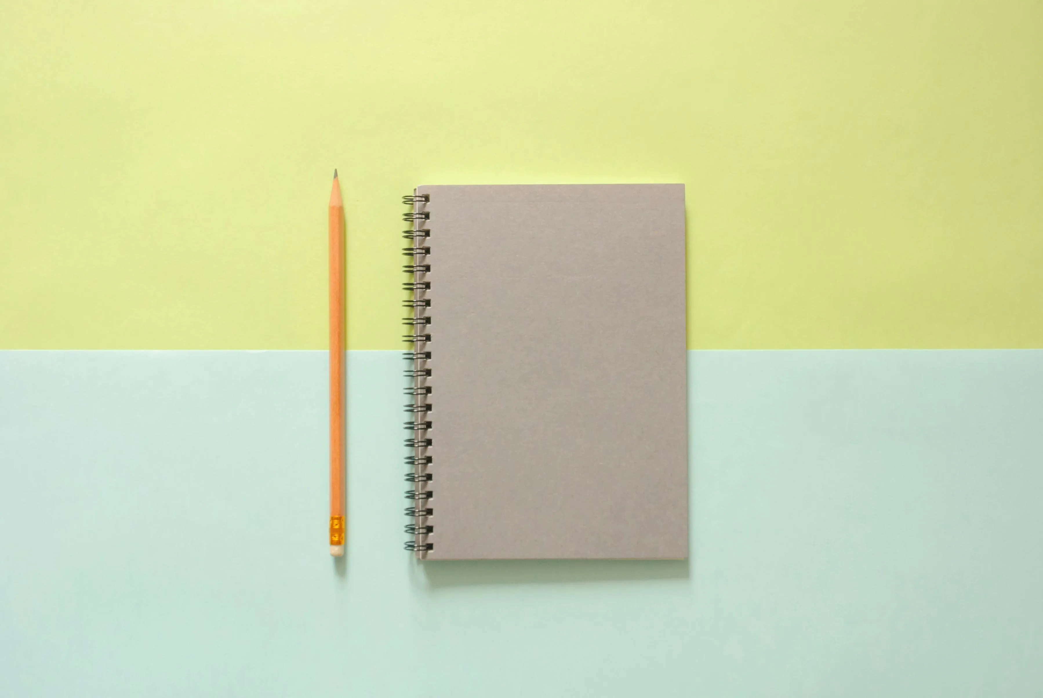 Notebook and pencil on a pastel yellow blue background 4K