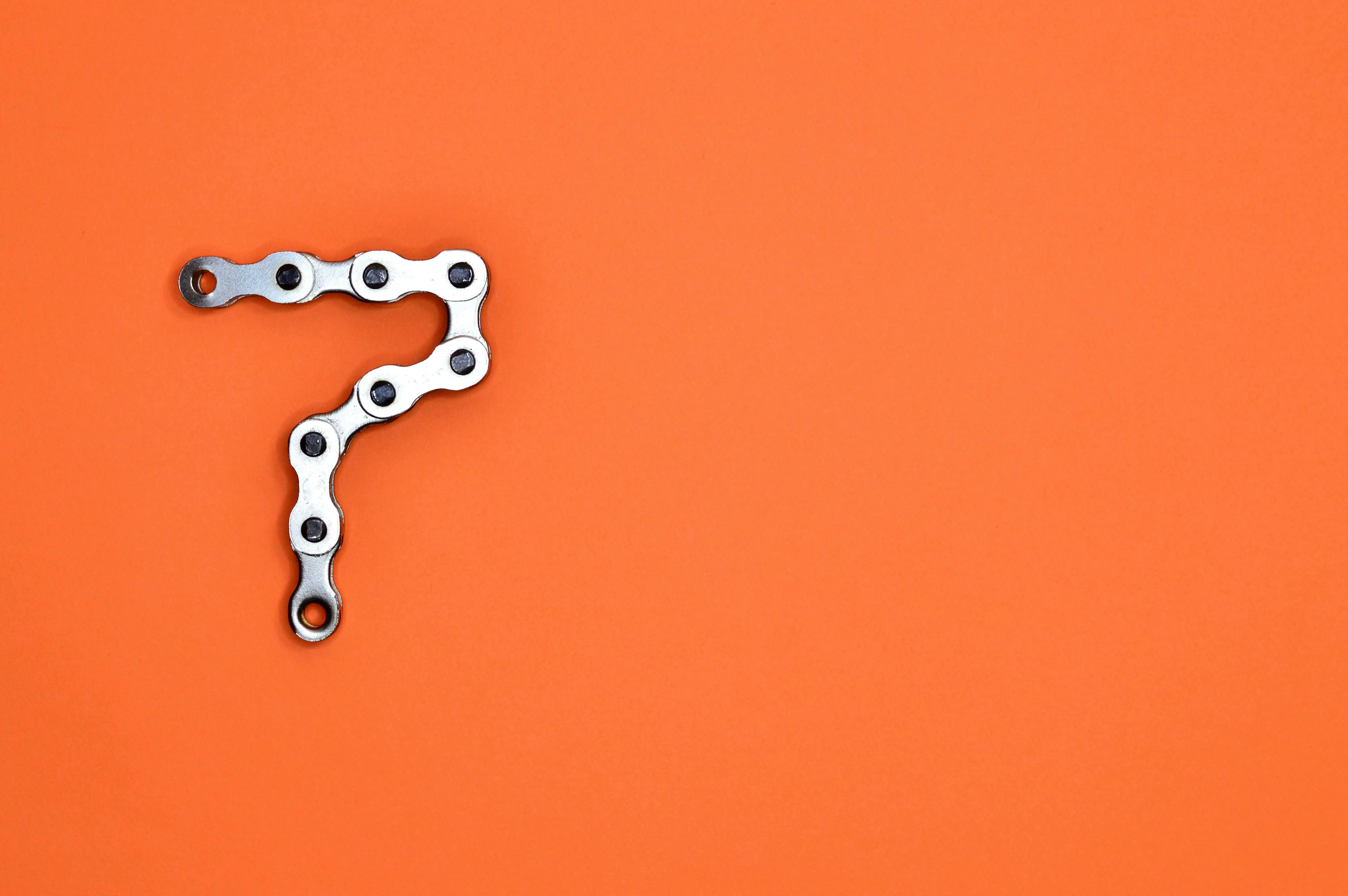 Number seven made with a bicycle chain on orange background