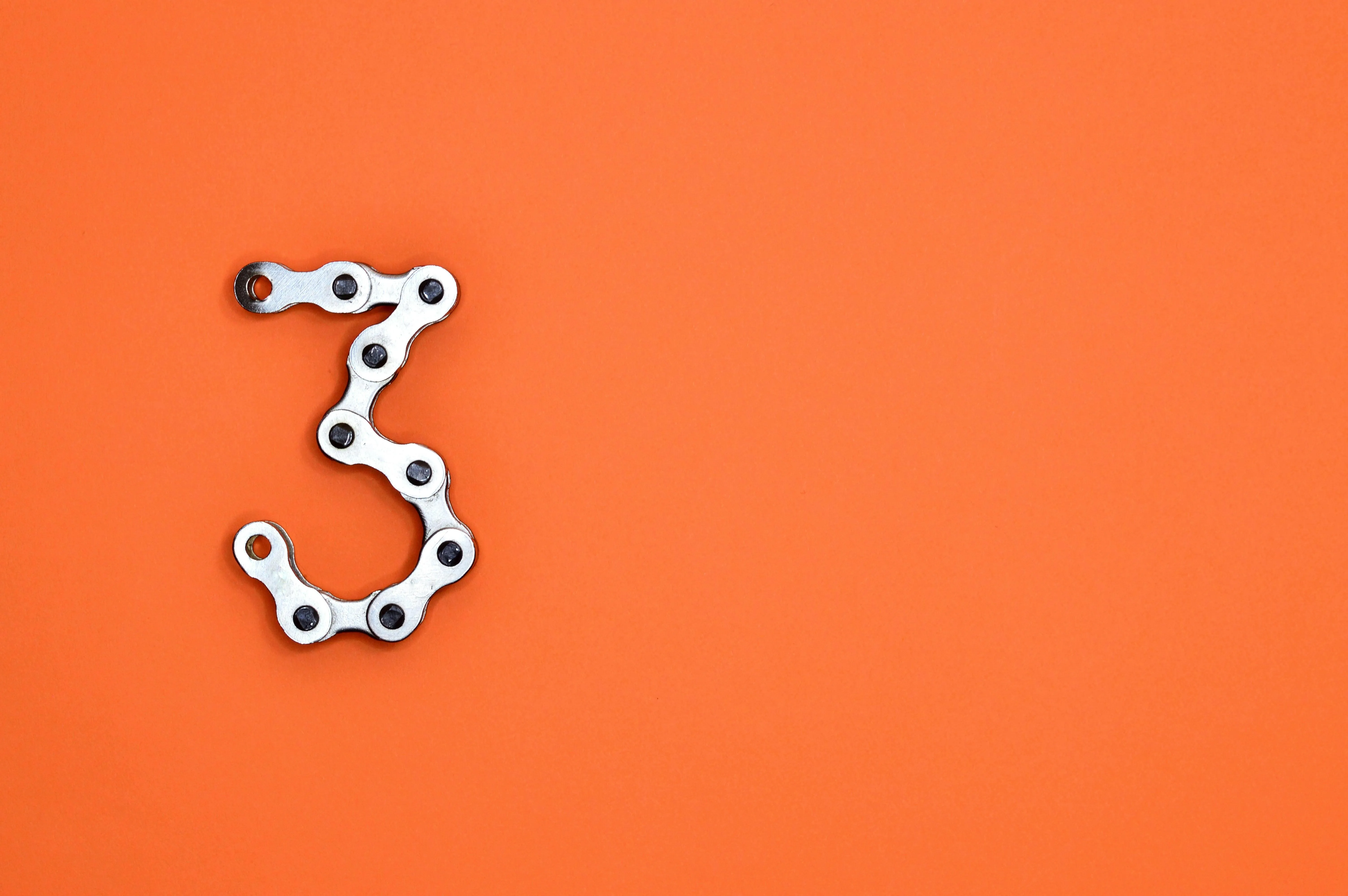 Number three formed with bicycle chain on orange background