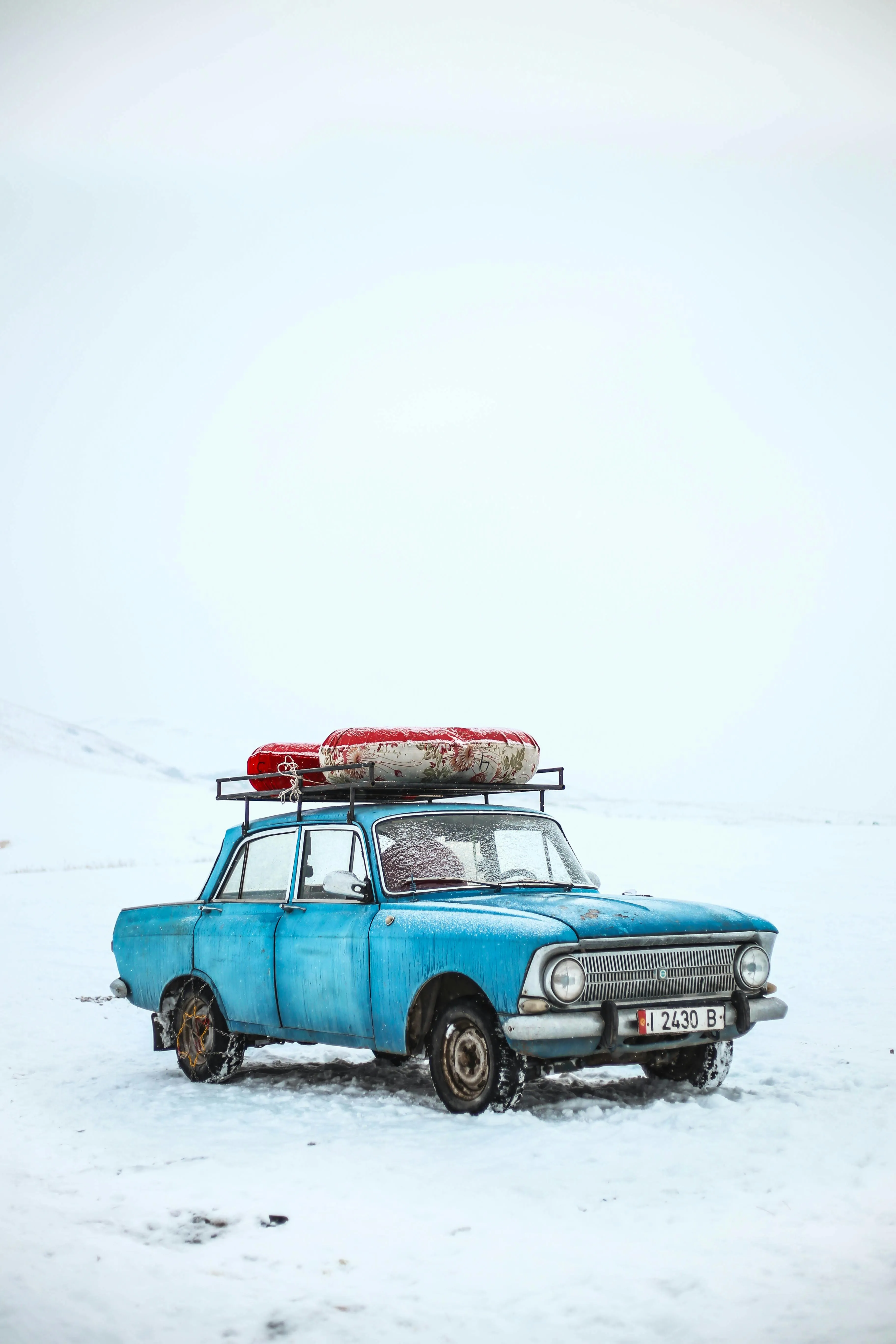 Old blue car parked on snowy road with winter luggage image