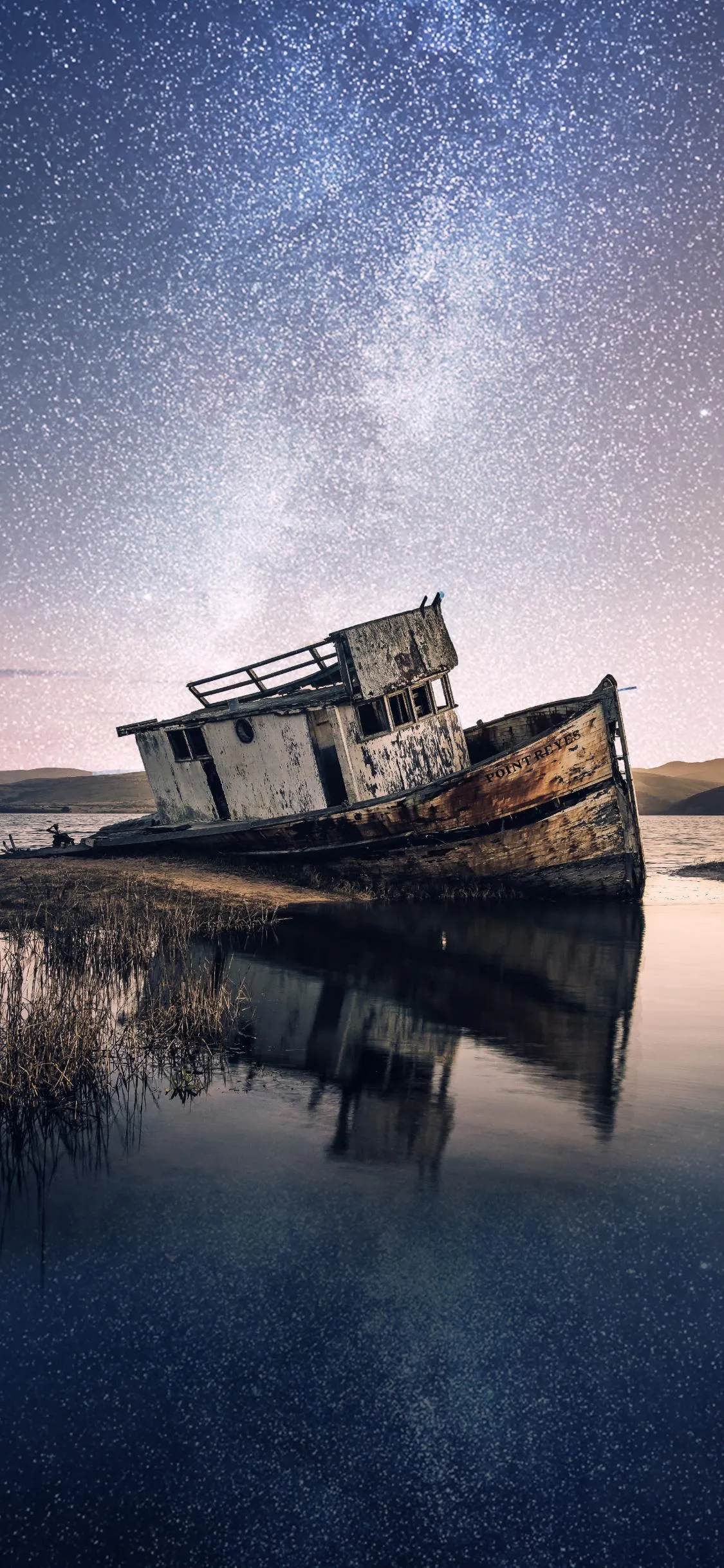 Old Shipwreck Reflecting in Calm Water Under Starry Night