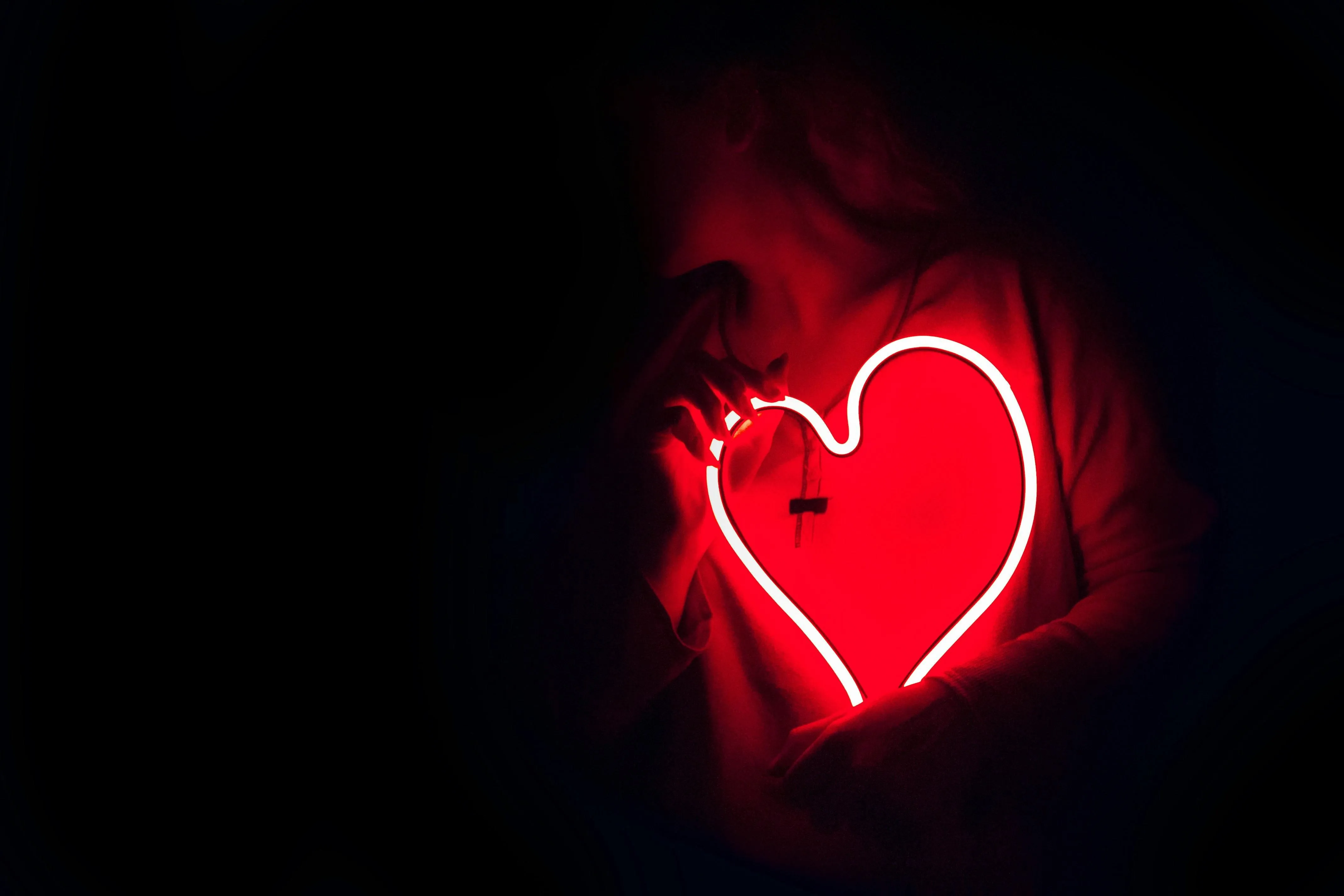 Outline of a person holding a glowing red neon heart image