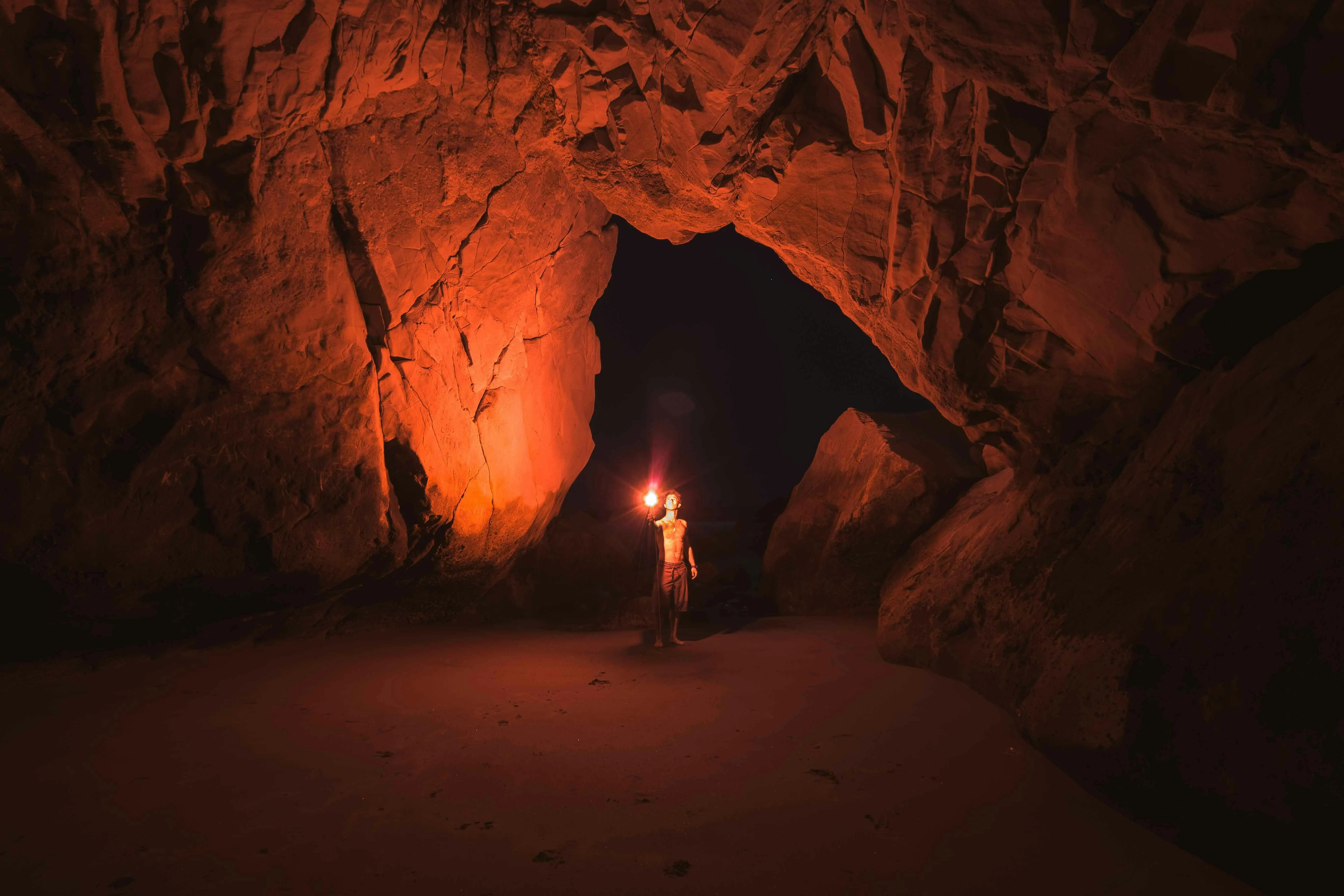 Person with a torch exploring a cave Background Wallpaper