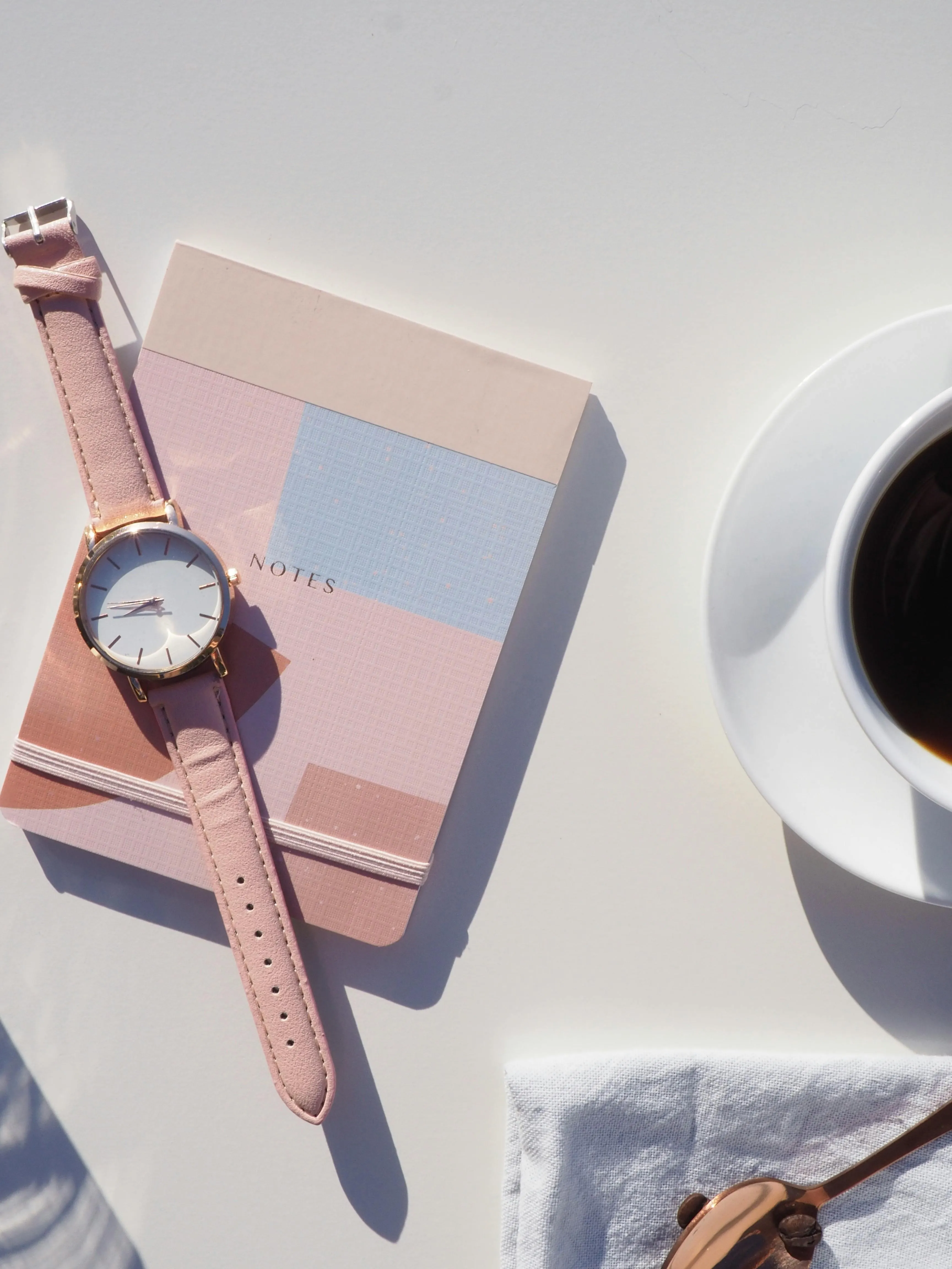 Pink watch notebook with coffee cup and spoon on table image