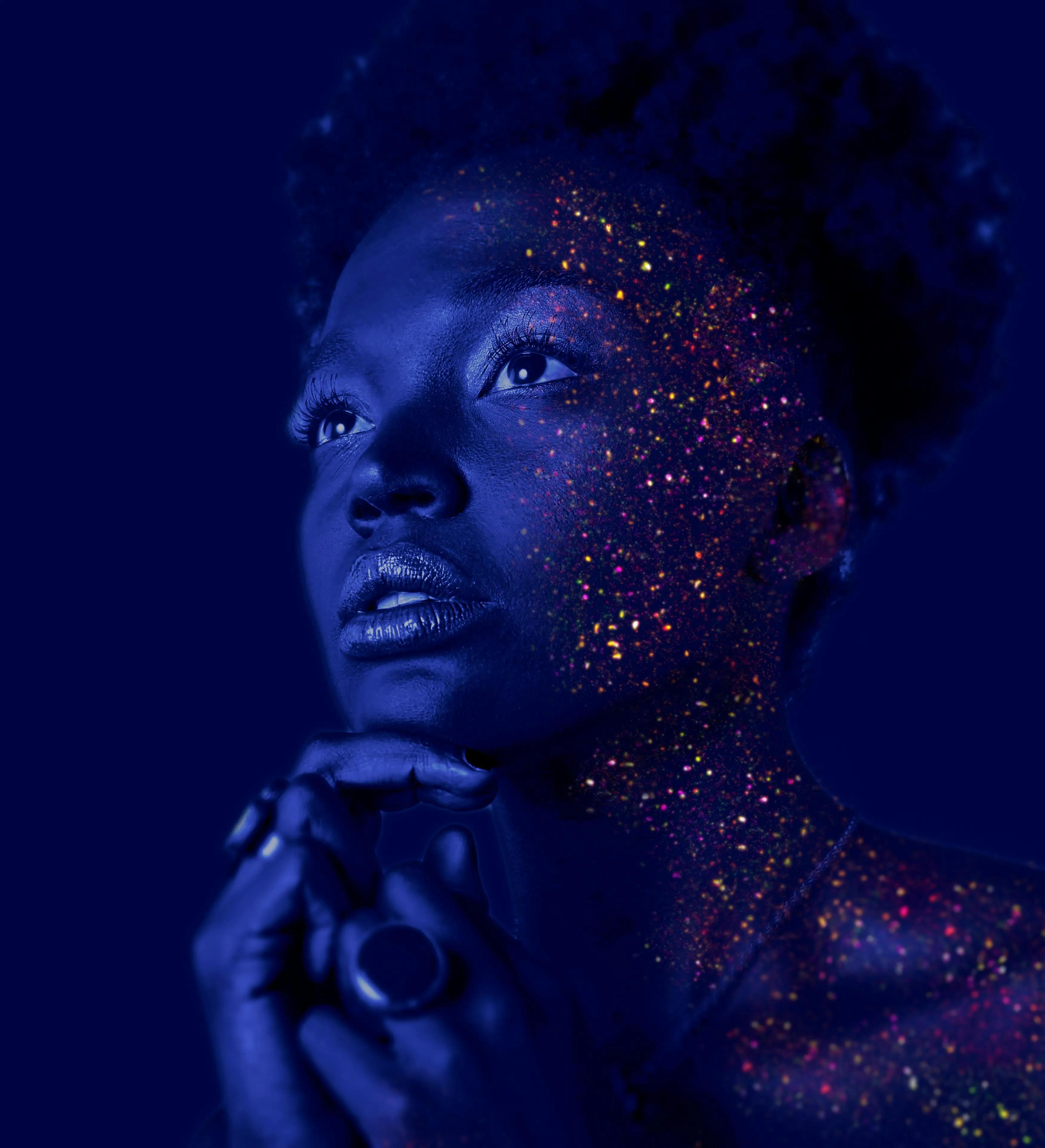 Portrait of thoughtful woman with glowing paint dots on face