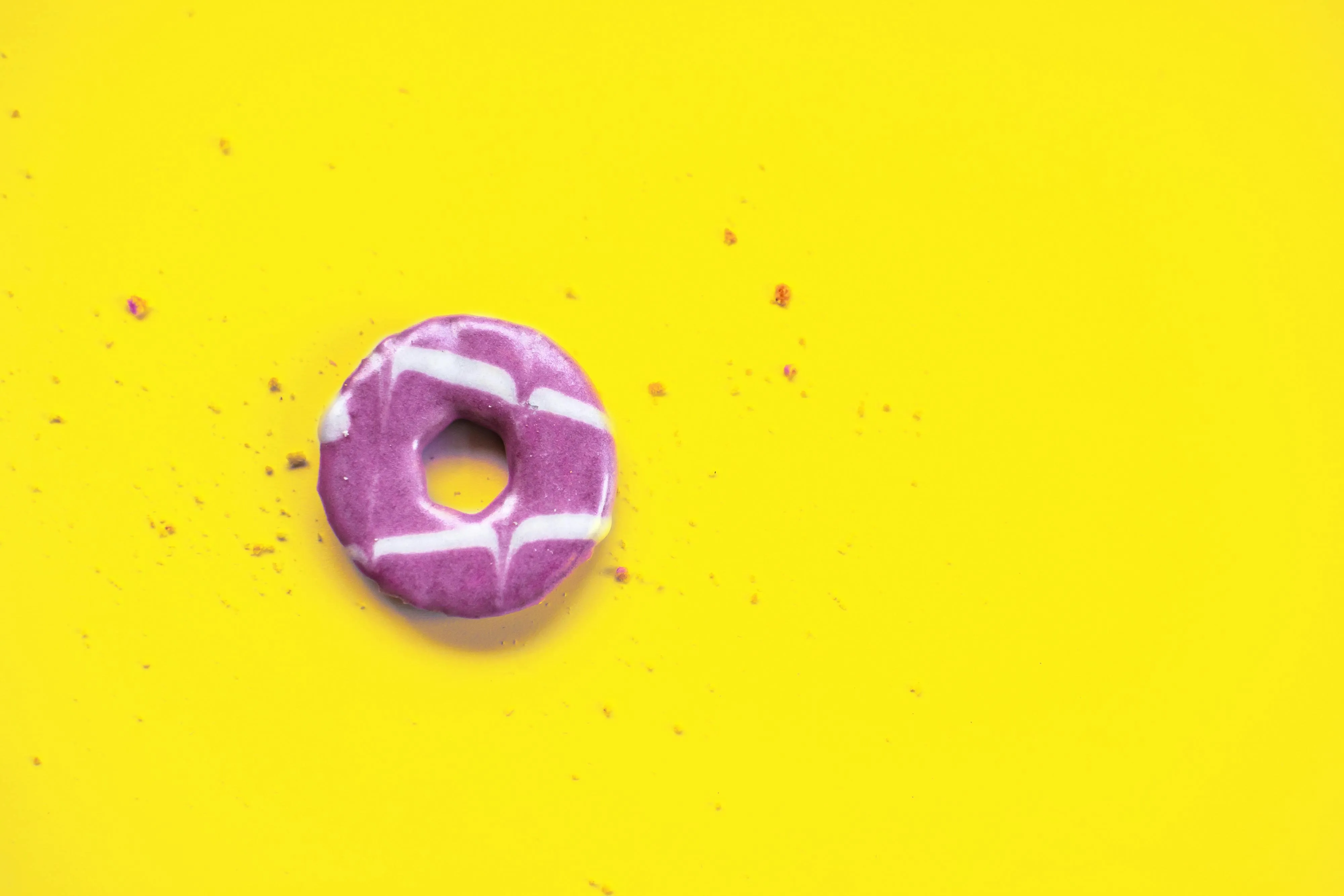 Purple frosted donut on a bright yellow background Wallpaper
