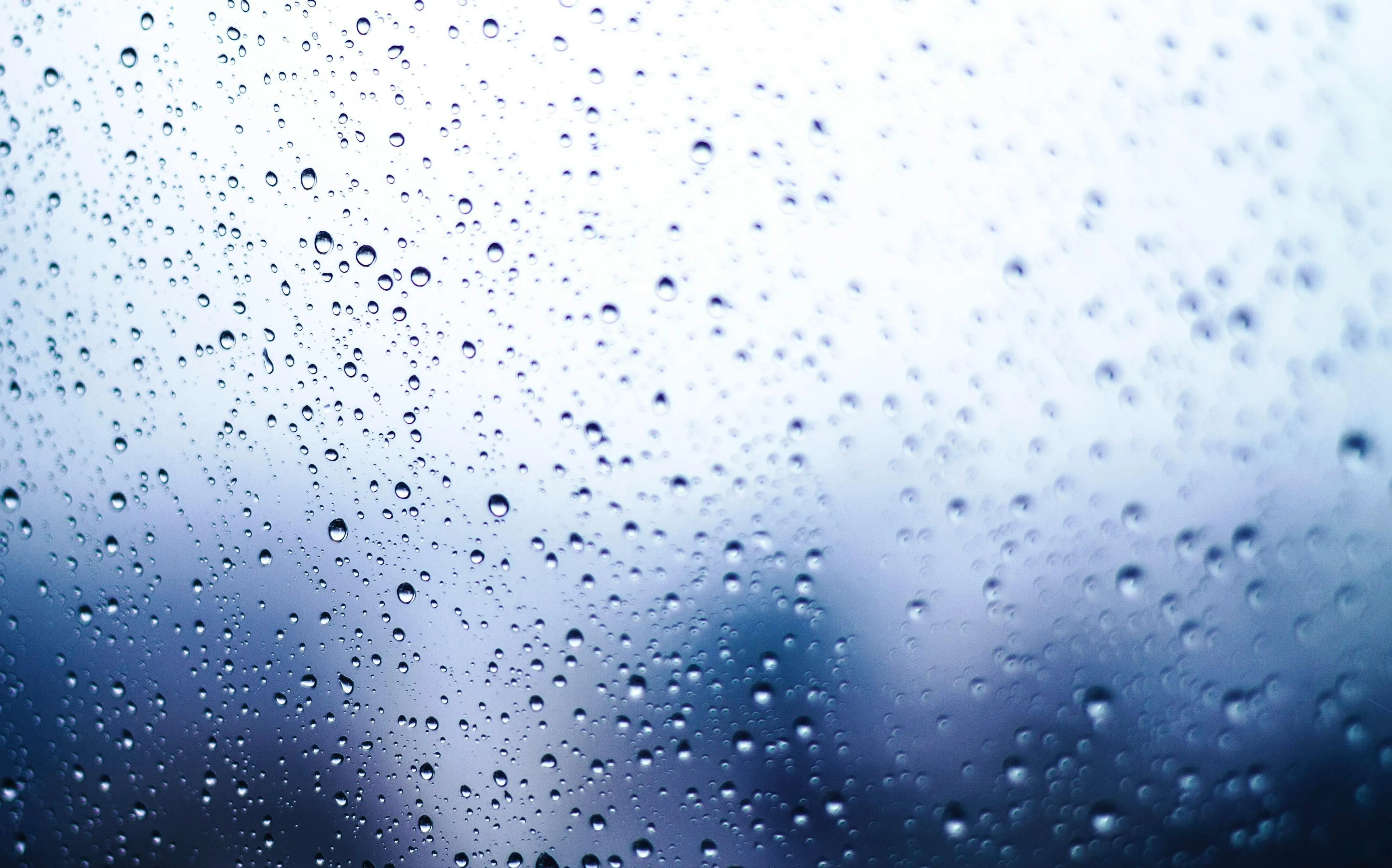 Raindrops on glass with blurred background 4K Wallpaper