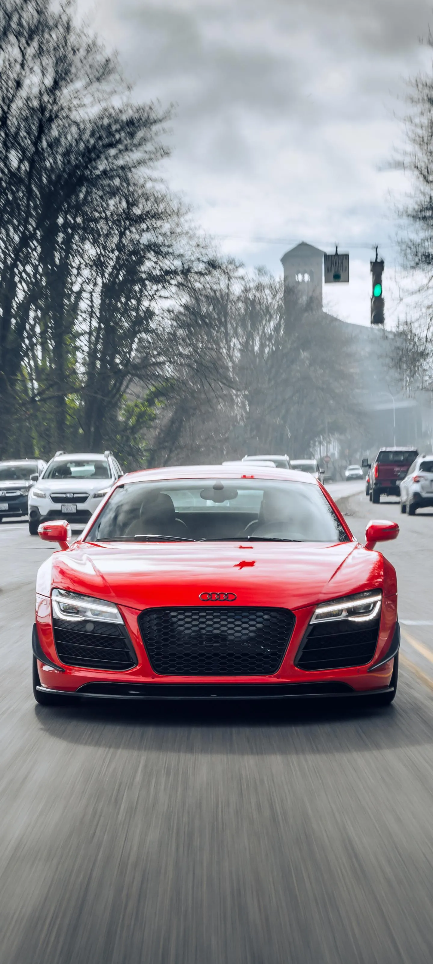 Red Sports Car Driving on Rainy Urban Street Wallpaper