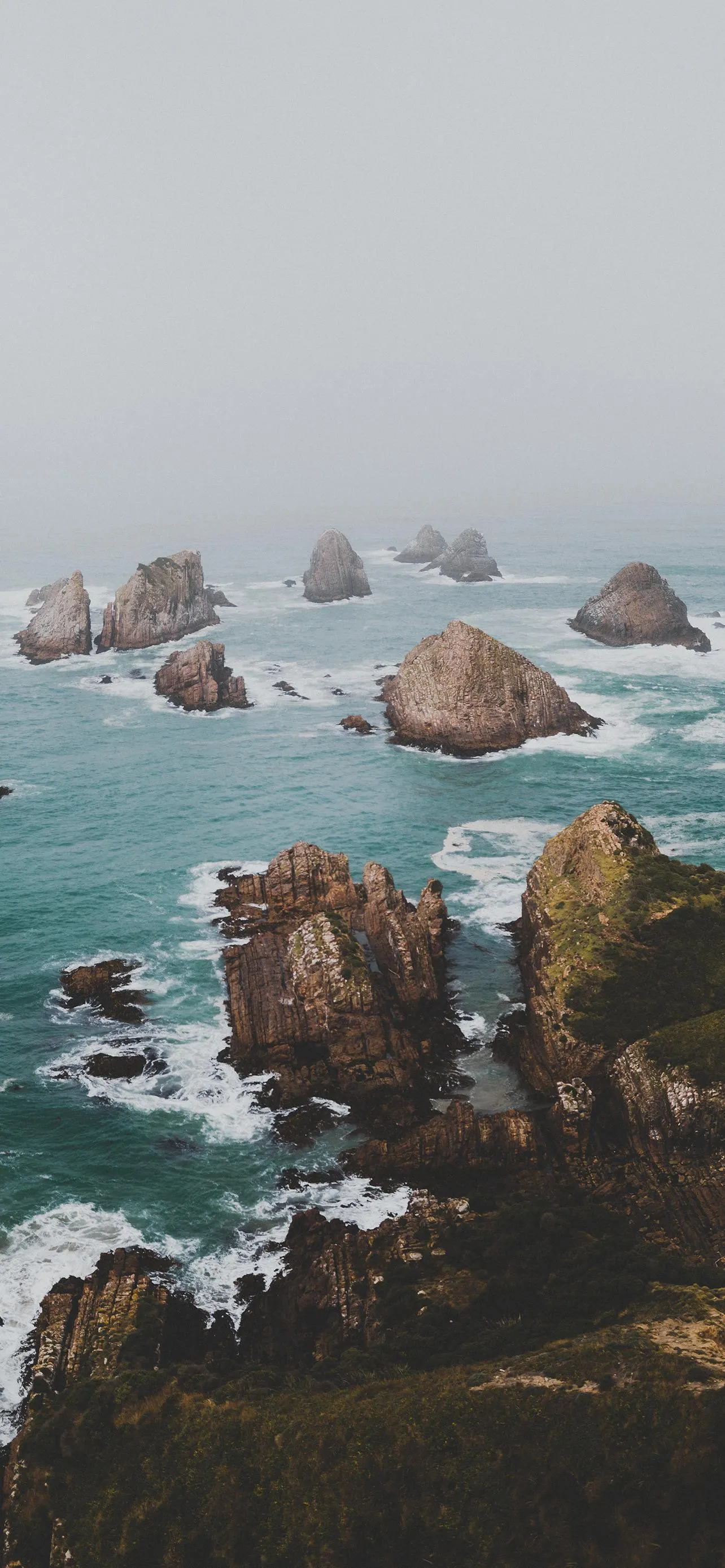 Rocky Coastline with Calm Sea and Overcast Sky Mobile