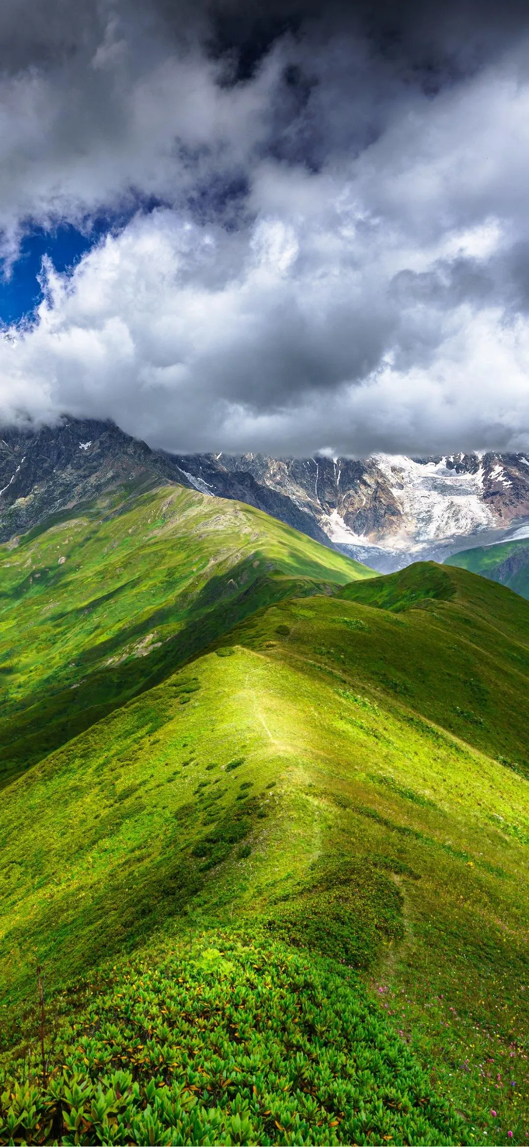 Rolling Green Hills Under Dramatic Cloudy Sky Wallpaper