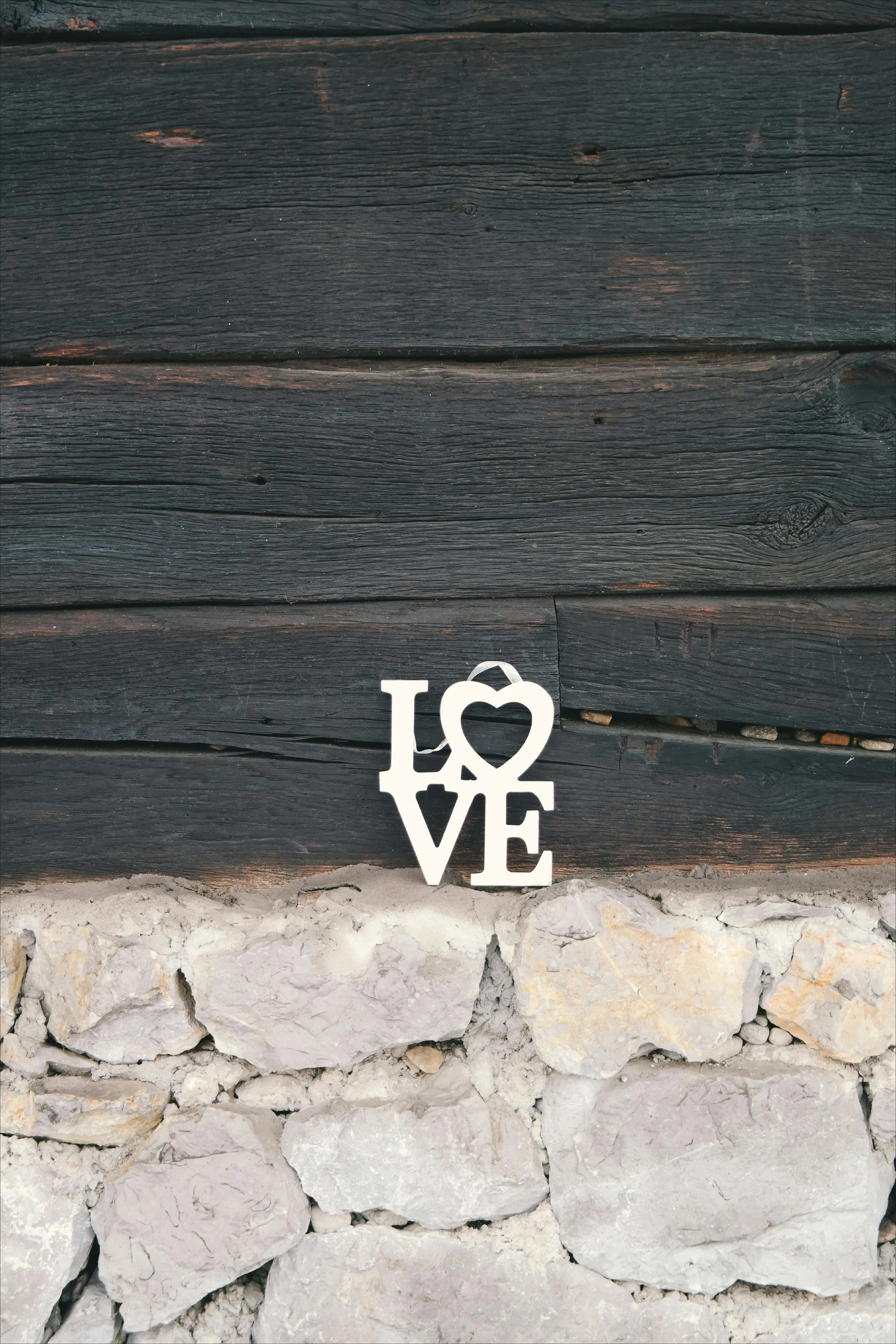 Rustic wooden wall with LOVE sign on a stone base Wallpaper