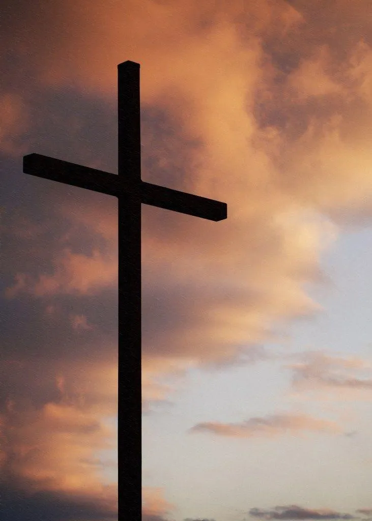 Silhouette of a Christian cross at sunset with a cloudy sky