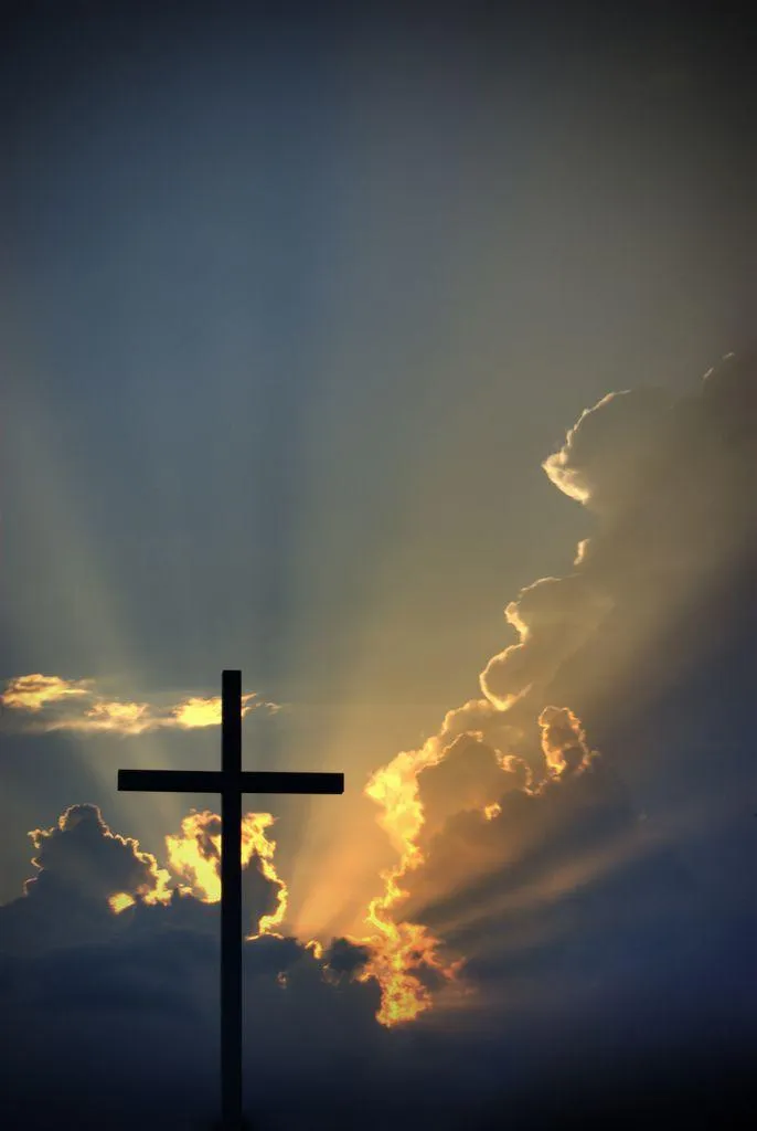 Silhouette of a cross with dramatic sunlight and clouds