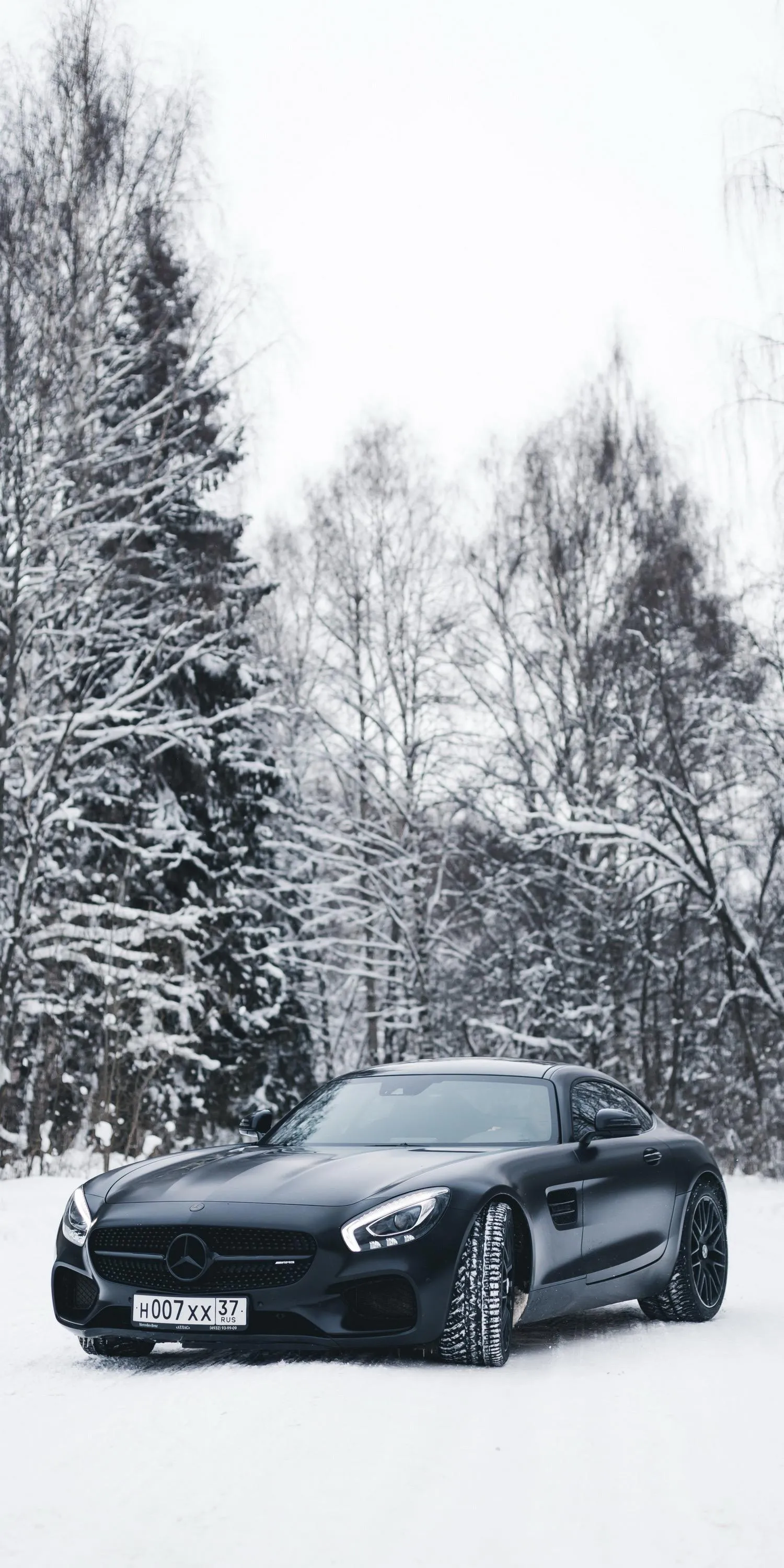 Sleek Car Parked in Snowy Forest Landscape Wallpaper