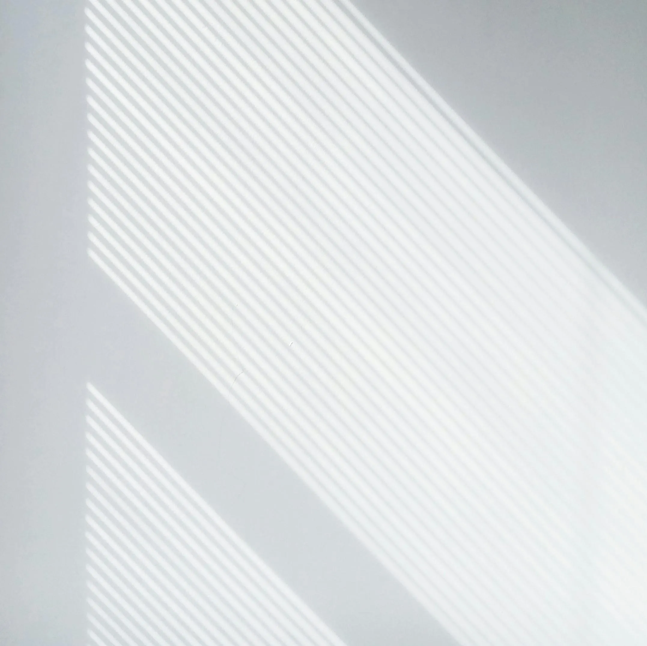 Soft natural light casting shadows on a white surface HD