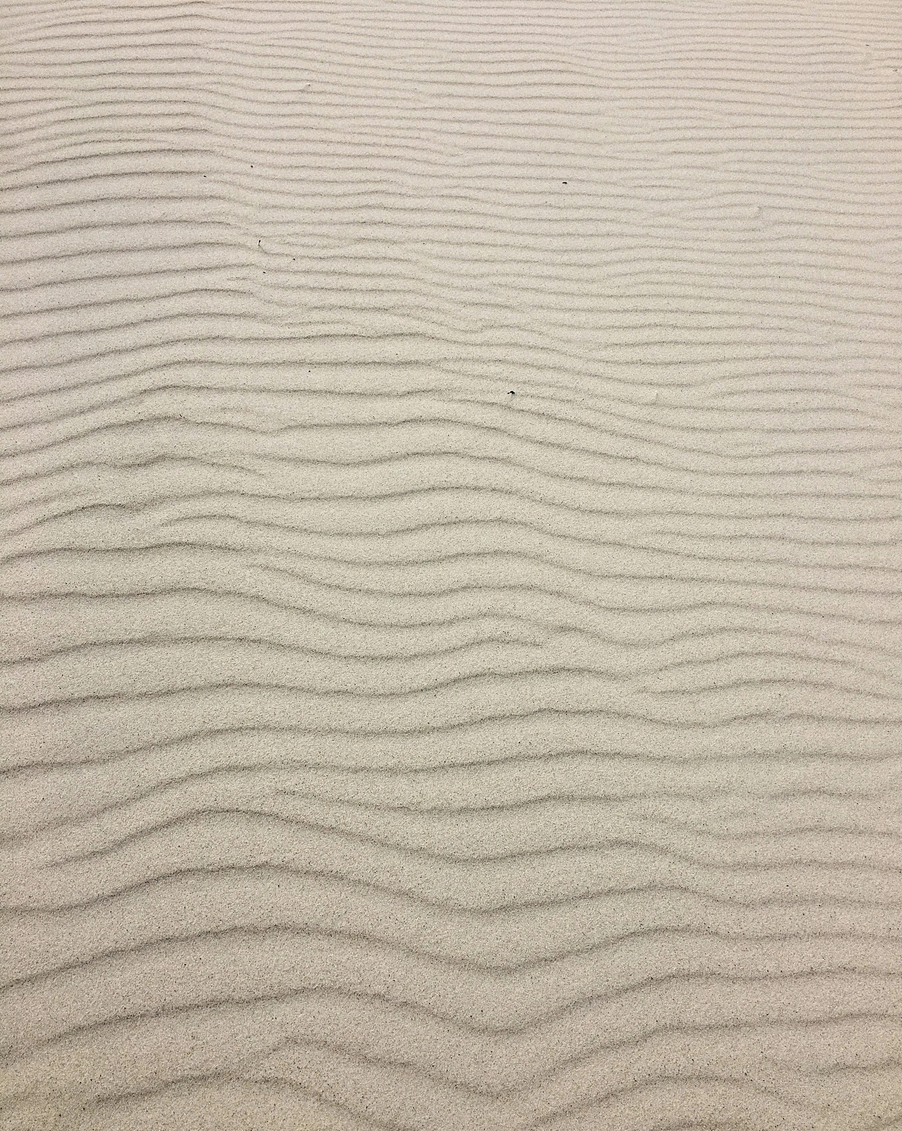 Soft sand waves pattern on a calm beach surface Wallpaper
